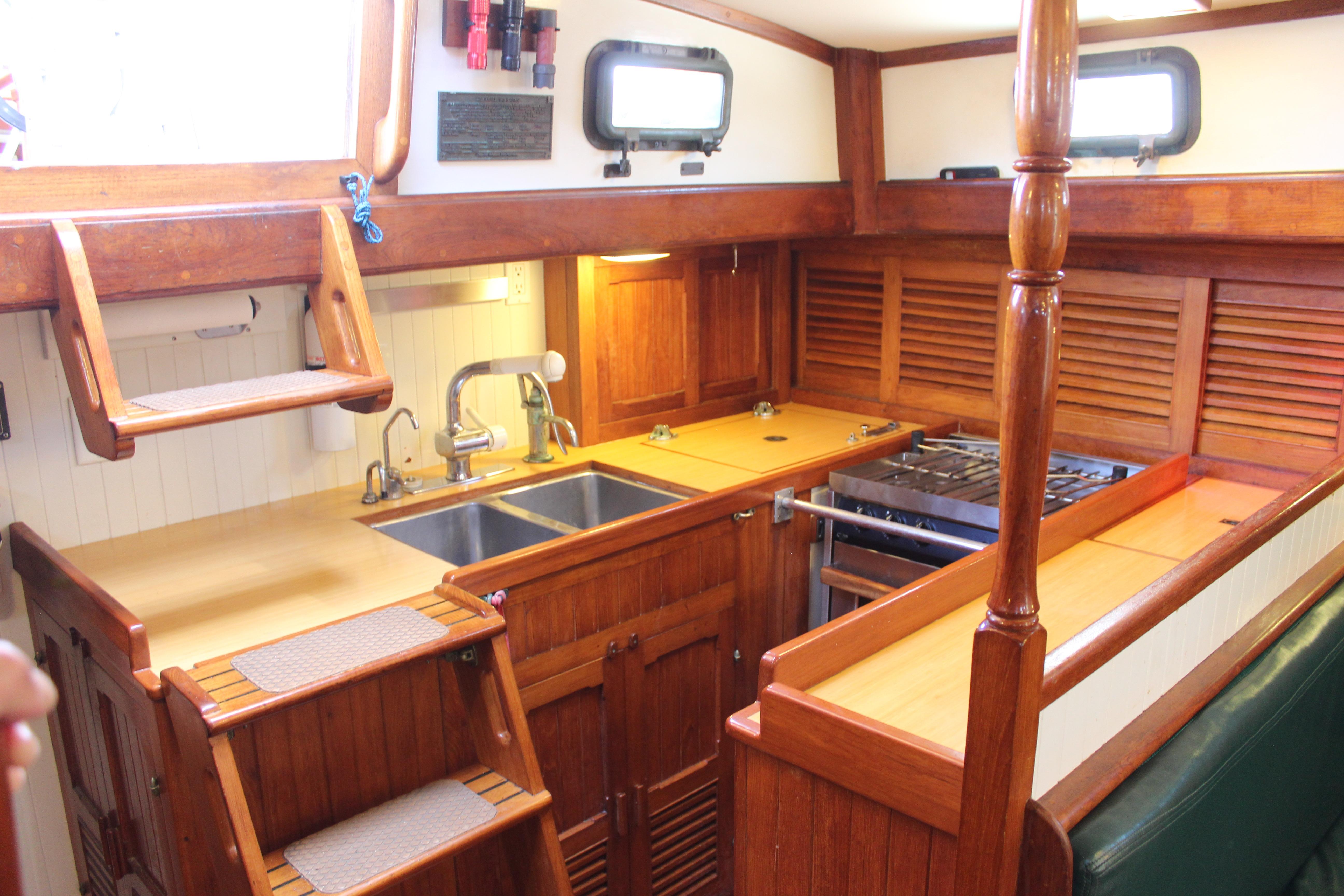 1981 Kelly Peterson 46 yacht galley with wooden cabinetry, dual sinks, and stove.
