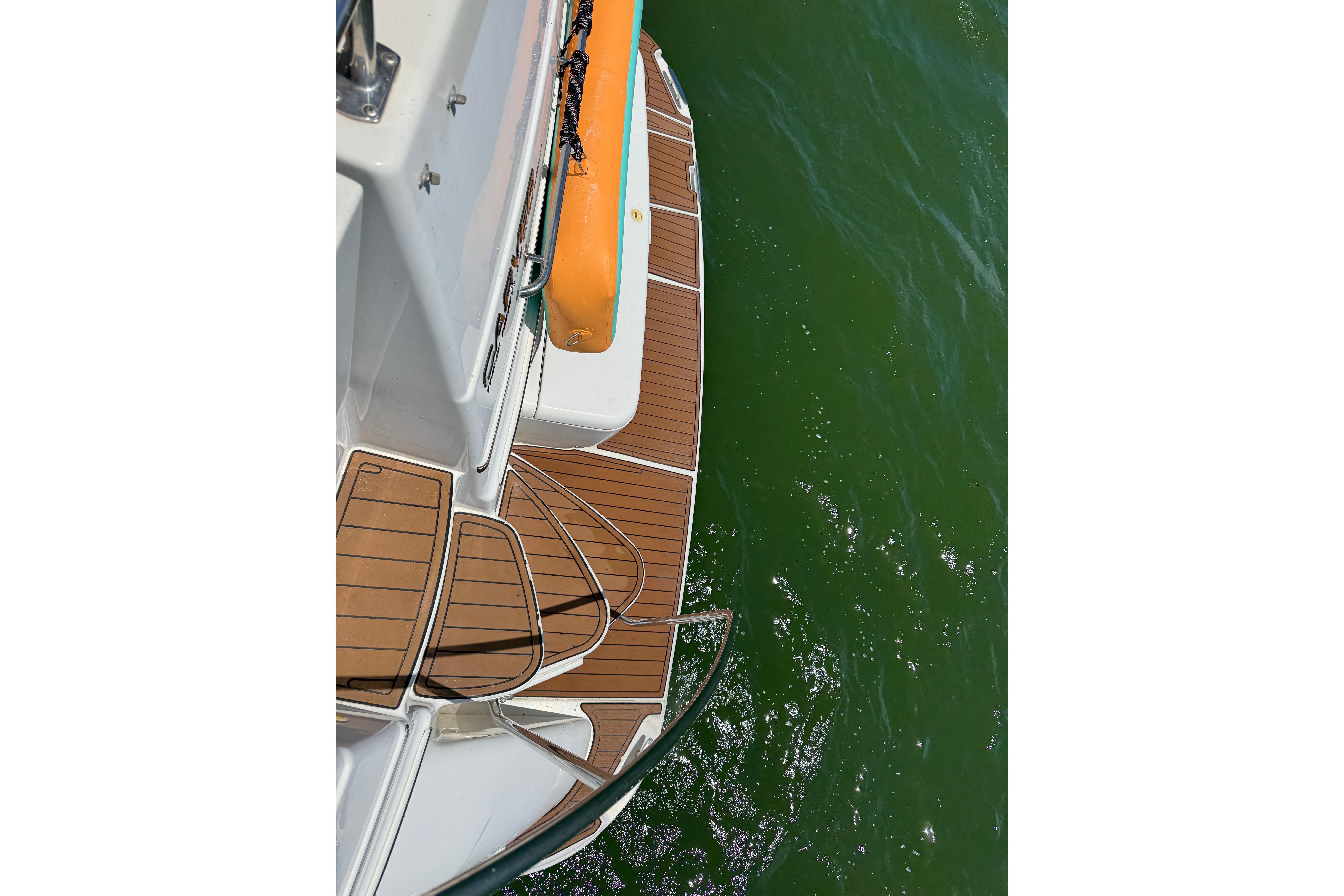 2002 Carver 396 Motor Yacht deck with wooden finish above green water.