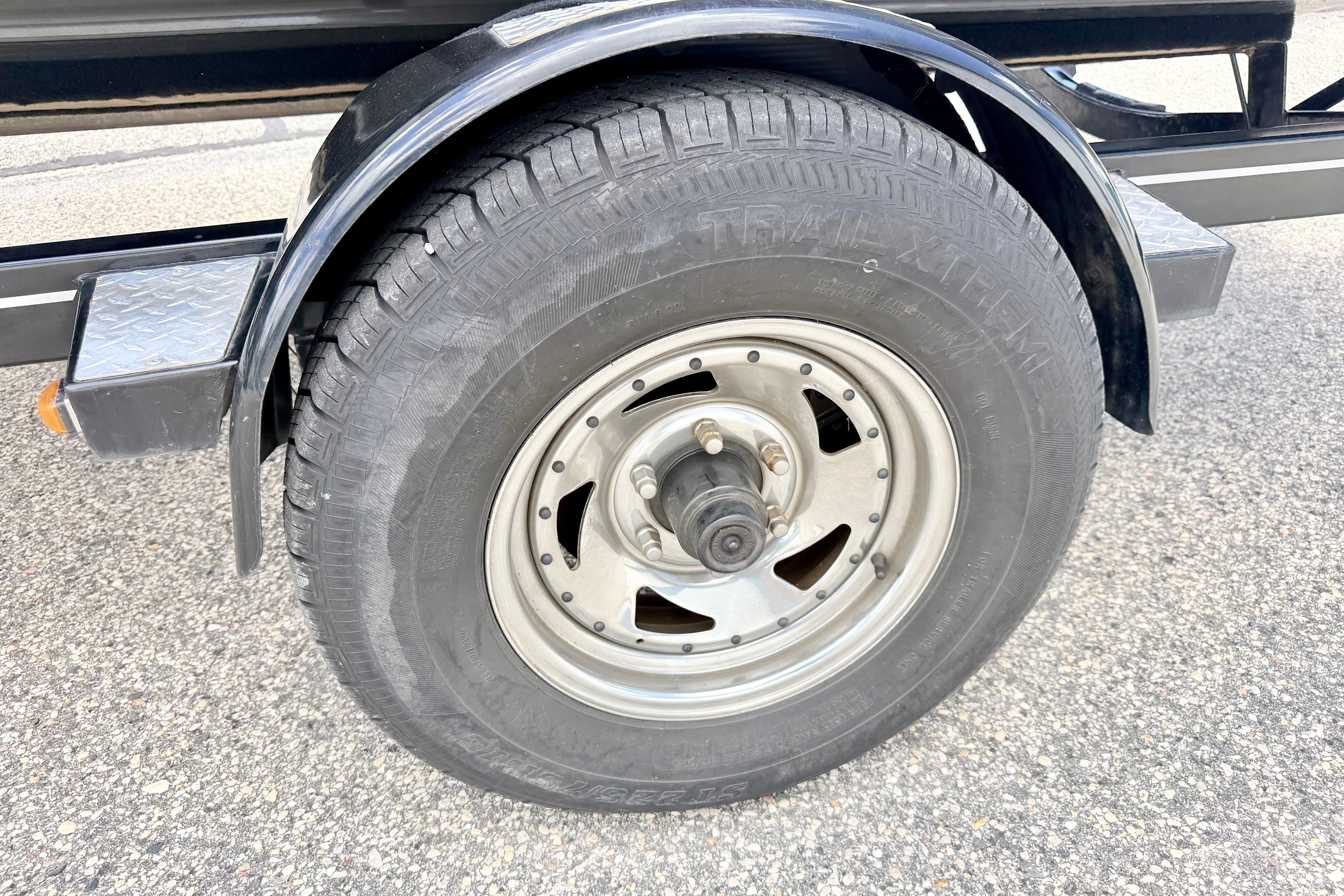 Trailer wheel of a 2018 Glastron GT 185 boat on pavement.