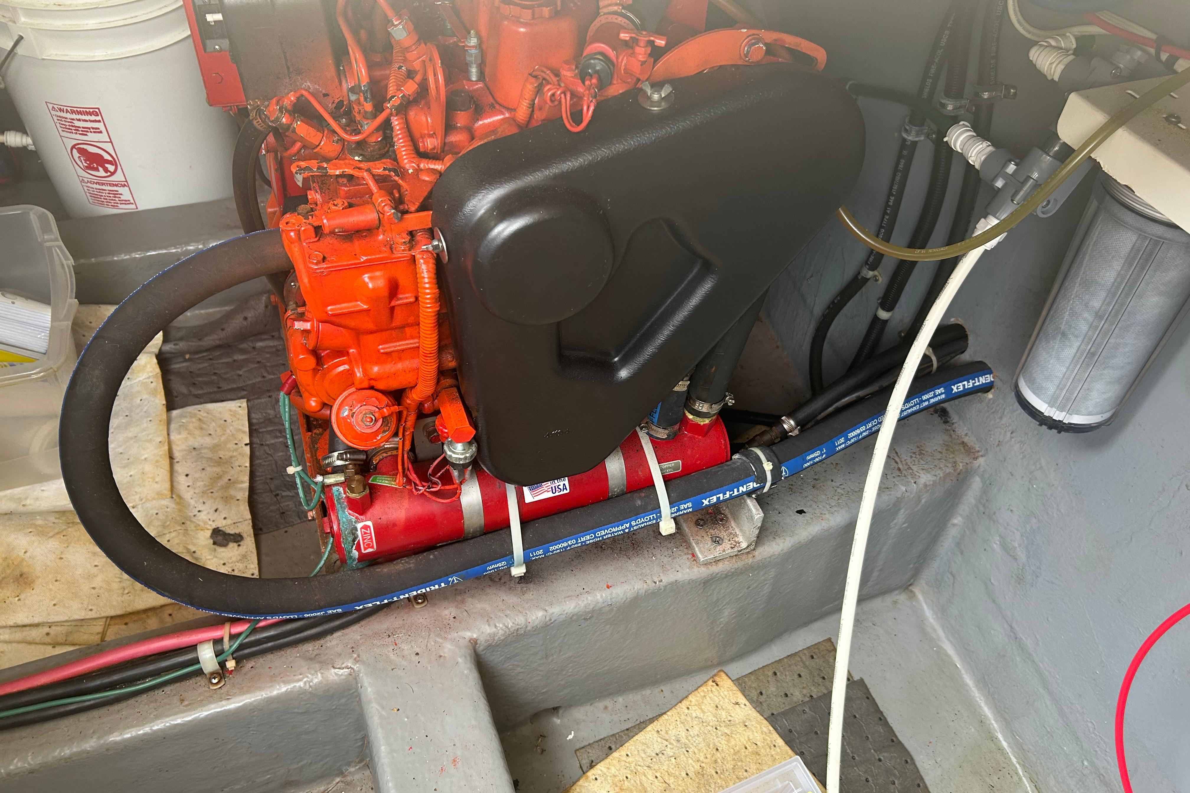2006 Mariner Orient engine with red components and hoses in a boat compartment.