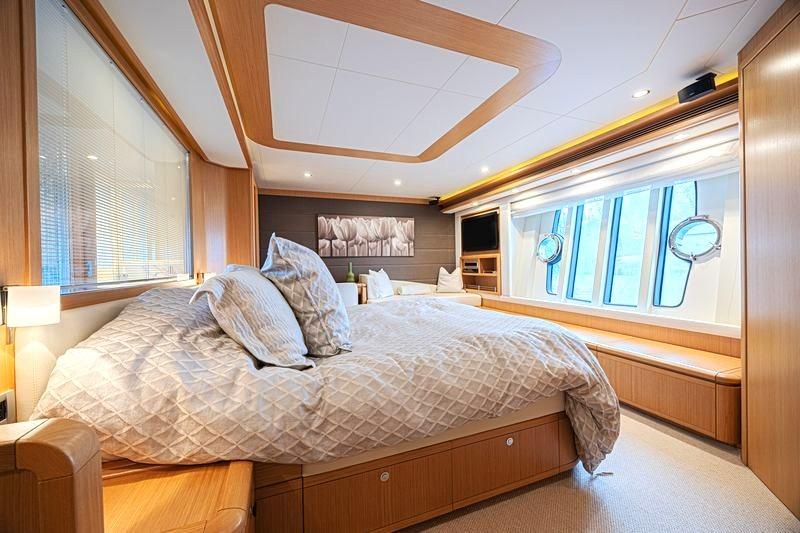 Luxurious bedroom interior of 2011 Ferretti Yachts 830 with elegant wood finishes and large windows.