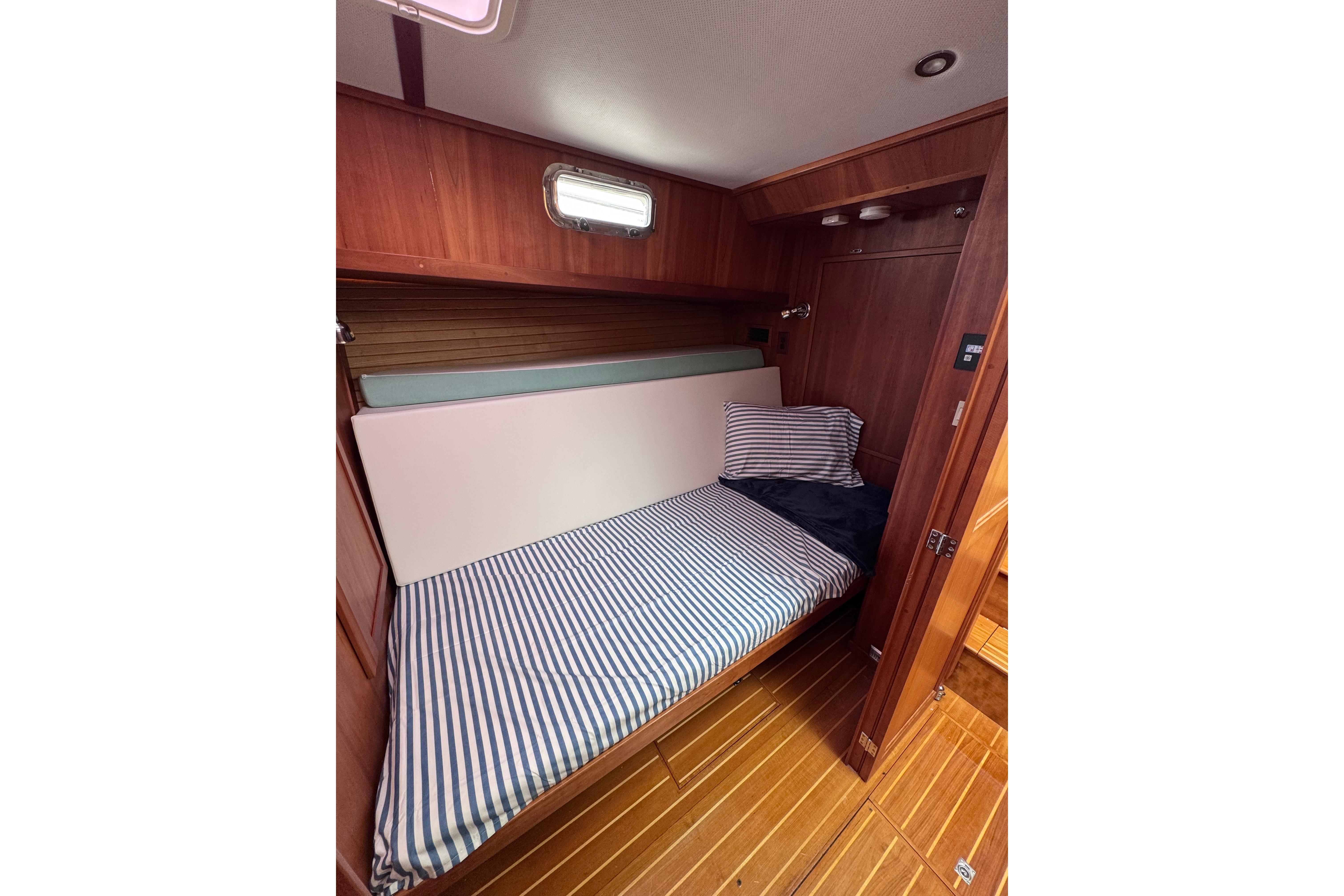 Cozy cabin interior of 2004 Sabre 42 Fly Bridge with striped bedding and wooden finish.