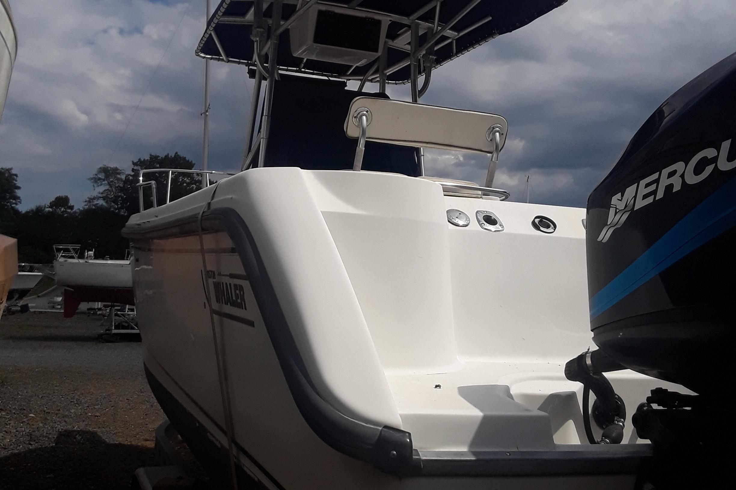 2001 Boston Whaler 260 Outrage boat with Mercury engine, docked under cloudy skies.