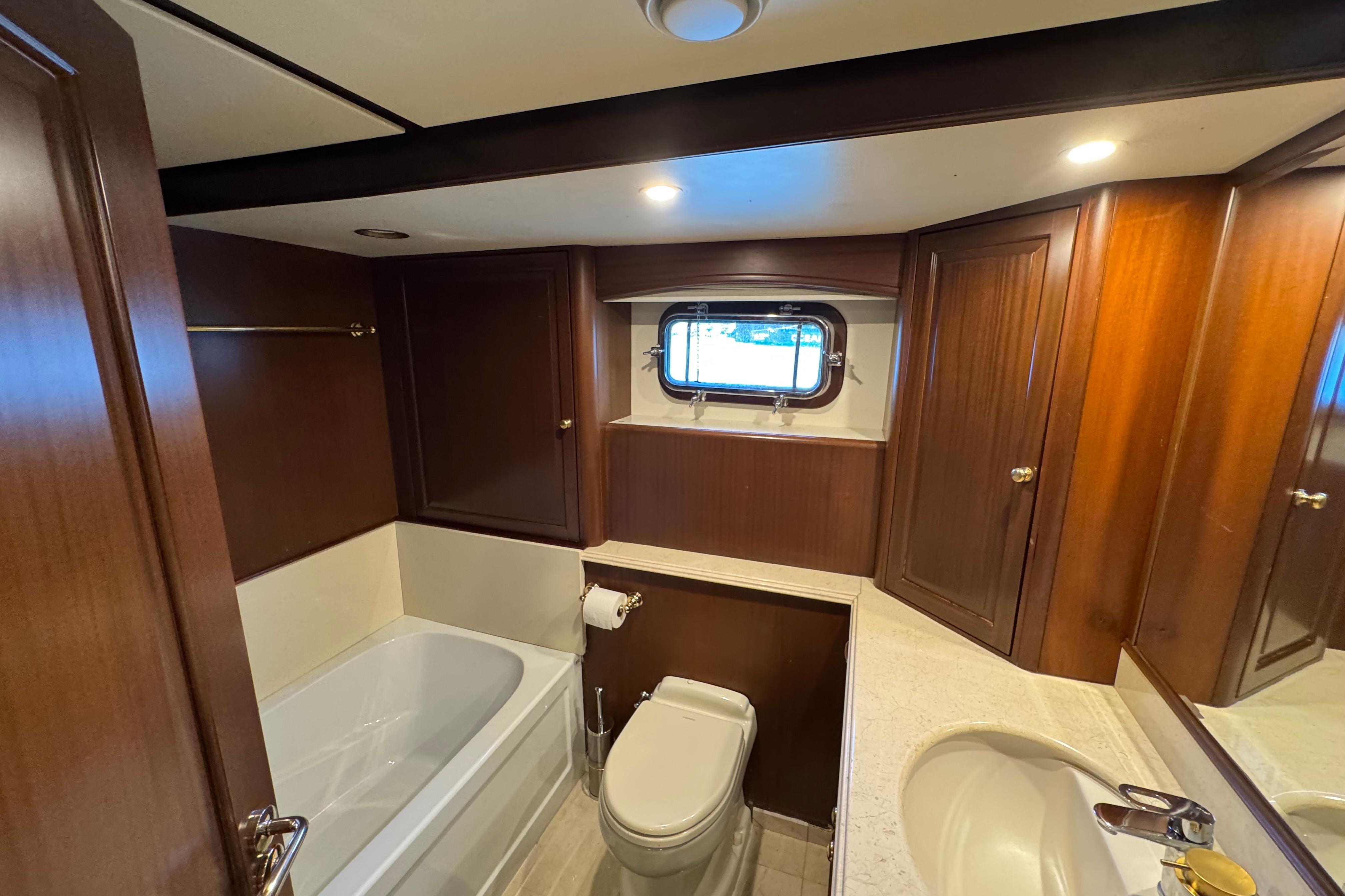 Luxurious yacht bathroom with wooden cabinets, bathtub, and porthole window, Doogersbank Vipack 2001 model.