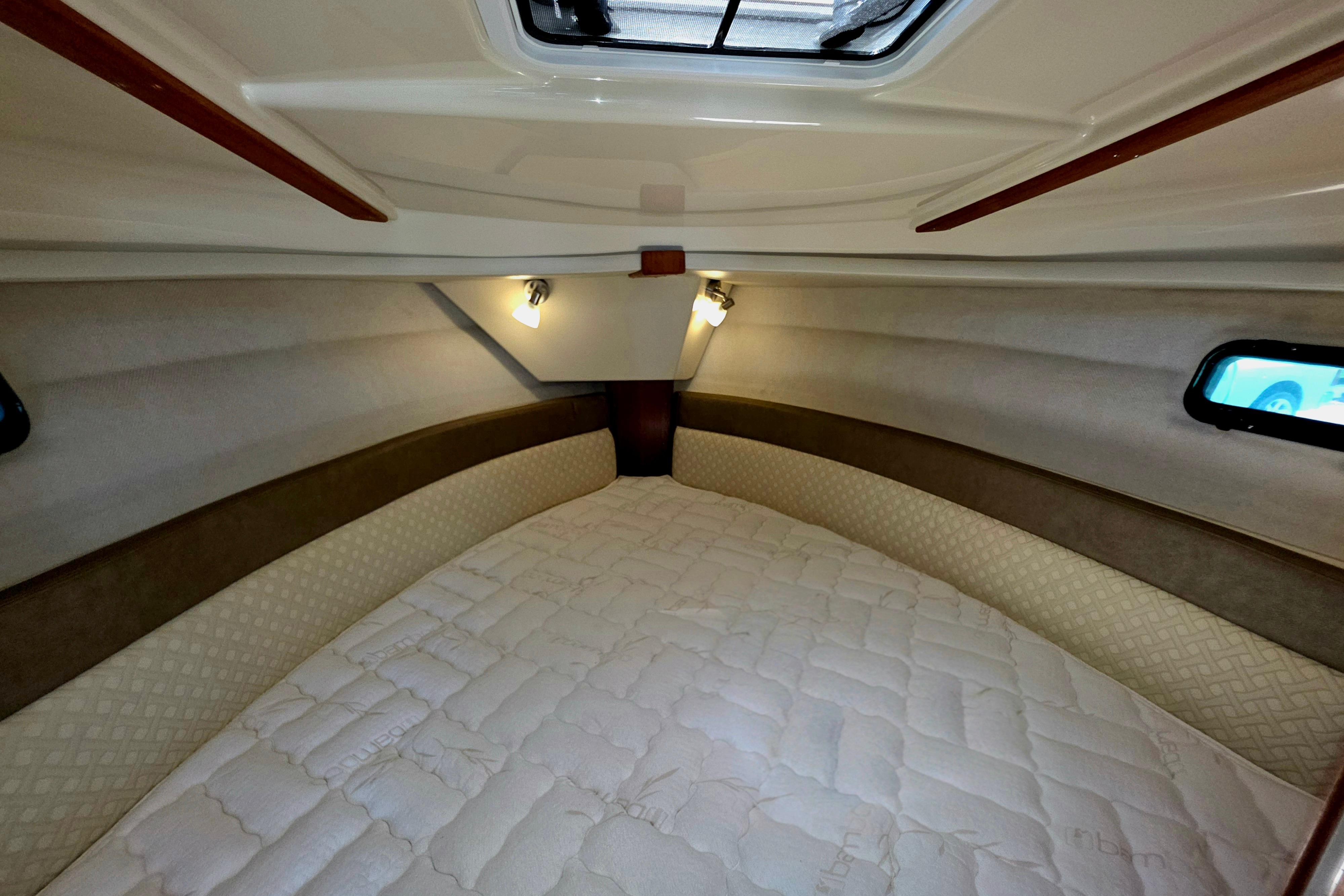 Cozy cabin interior of 2021 Ranger Tug R27 with comfortable bedding and ambient lighting.
