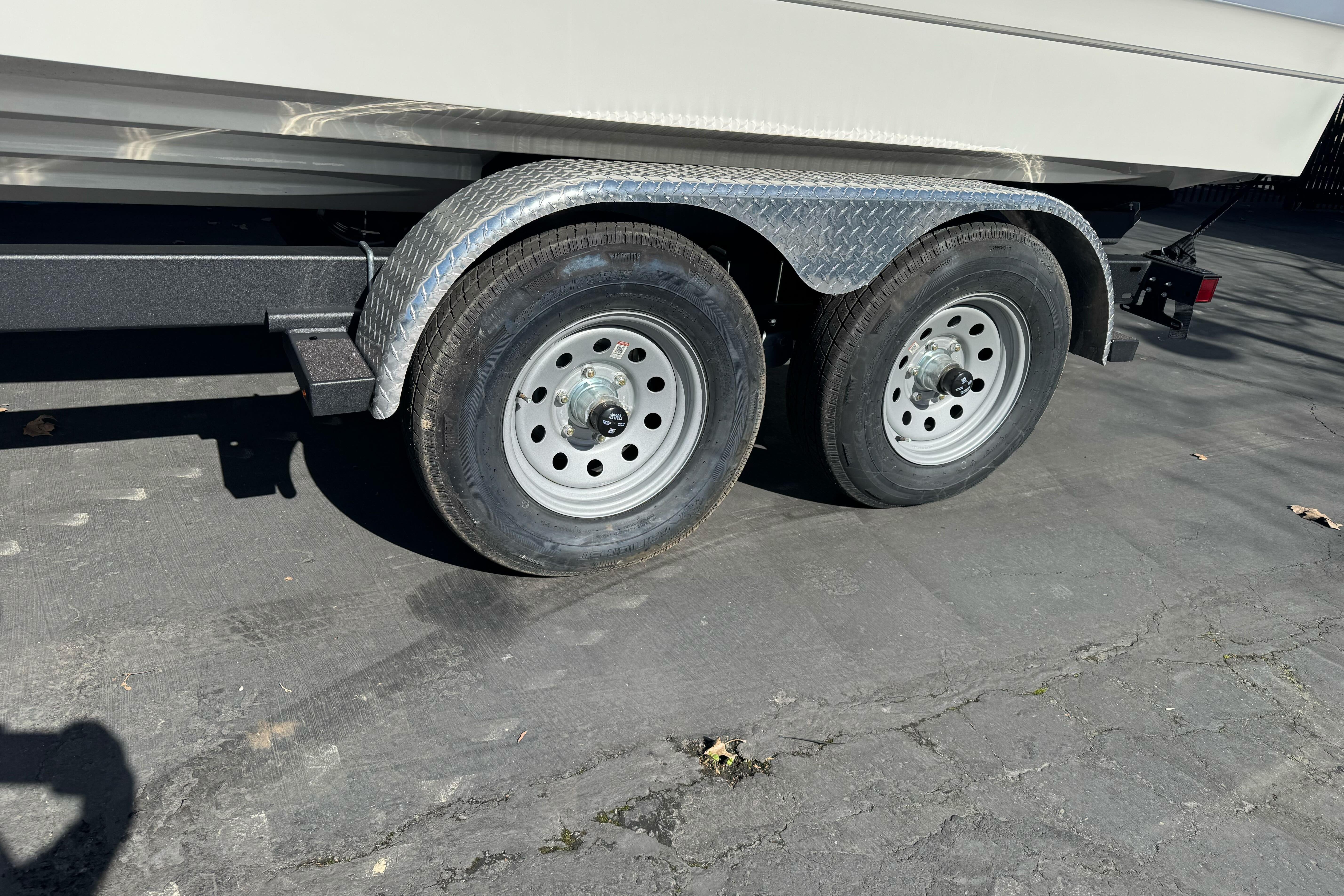 Trailer wheels of a 2026 Sea Ray SLX 260 boat on pavement.