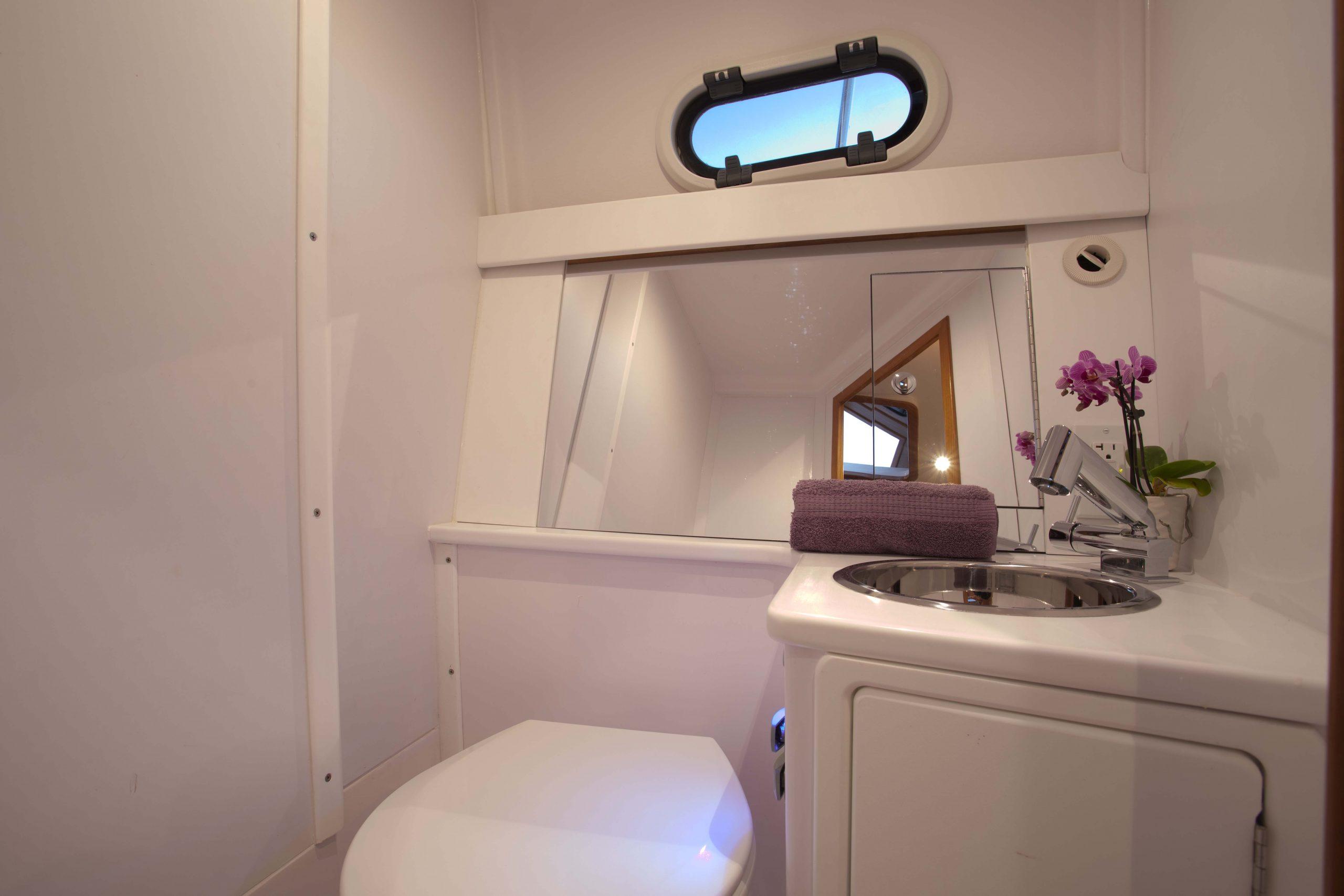 Modern bathroom in 2024 True North 34 boat with sink, mirror, and porthole window.