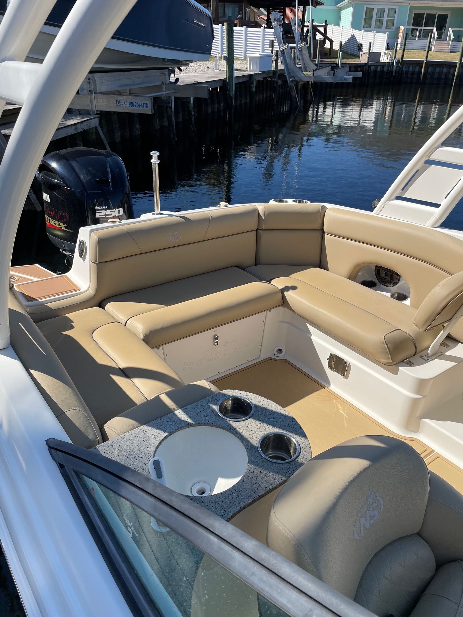 2019 NauticStar 243DC Sport Deck with beige seating, cup holders, and engine at the dock.