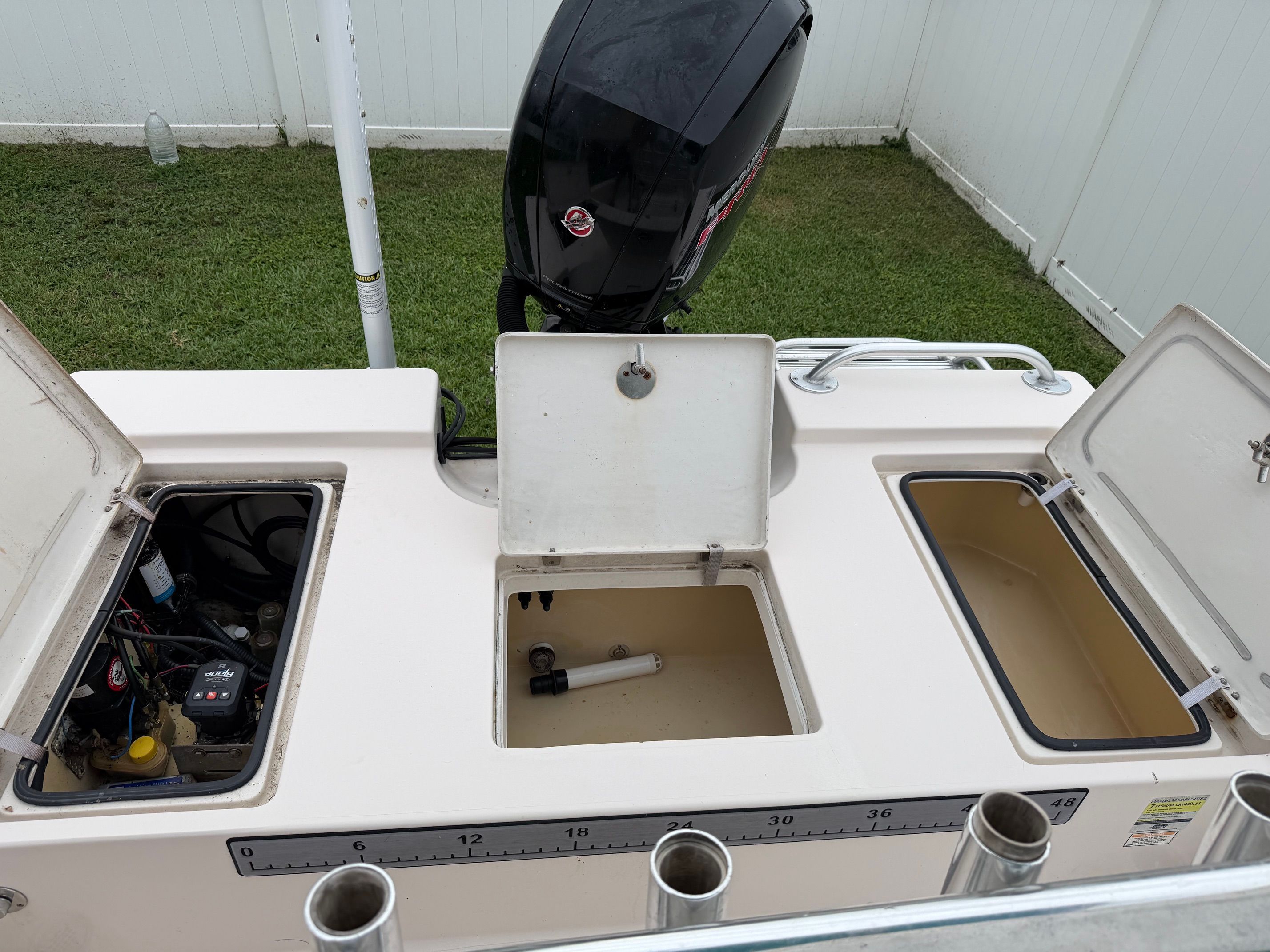 The image shows the stern of a boat with an outboard motor and several storage compartments.