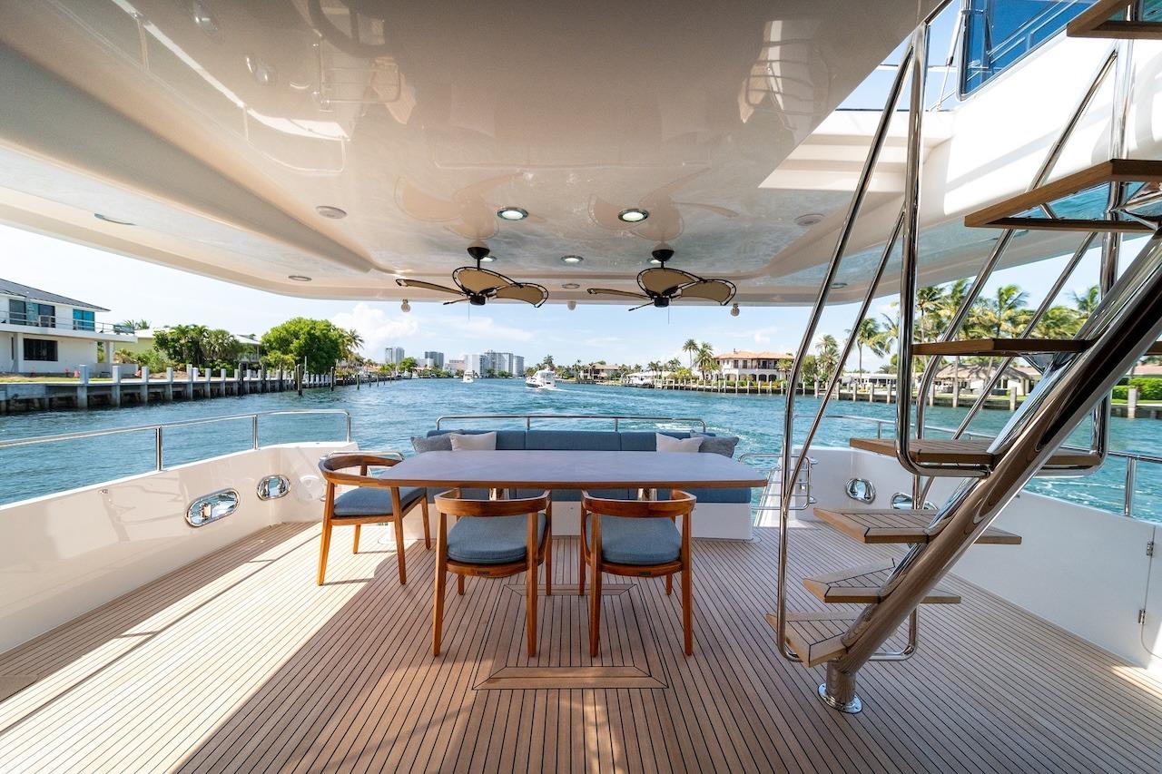 Luxurious 2027 Offshore Yachts 70 CE deck with elegant seating and scenic waterfront view.