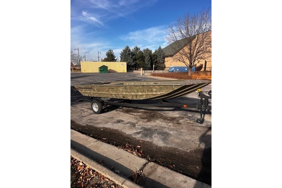 2025 Tracker Grizzly 1648 Jon boat on trailer in parking lot, clear sky background.