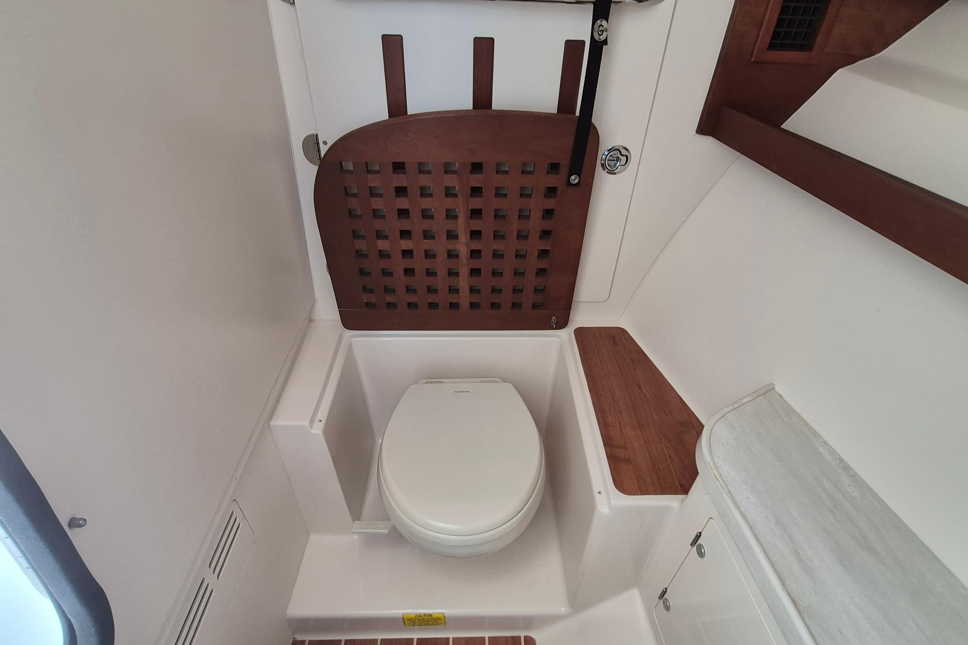 2019 Grady-White Freedom 335 boat bathroom with toilet and wooden accents.