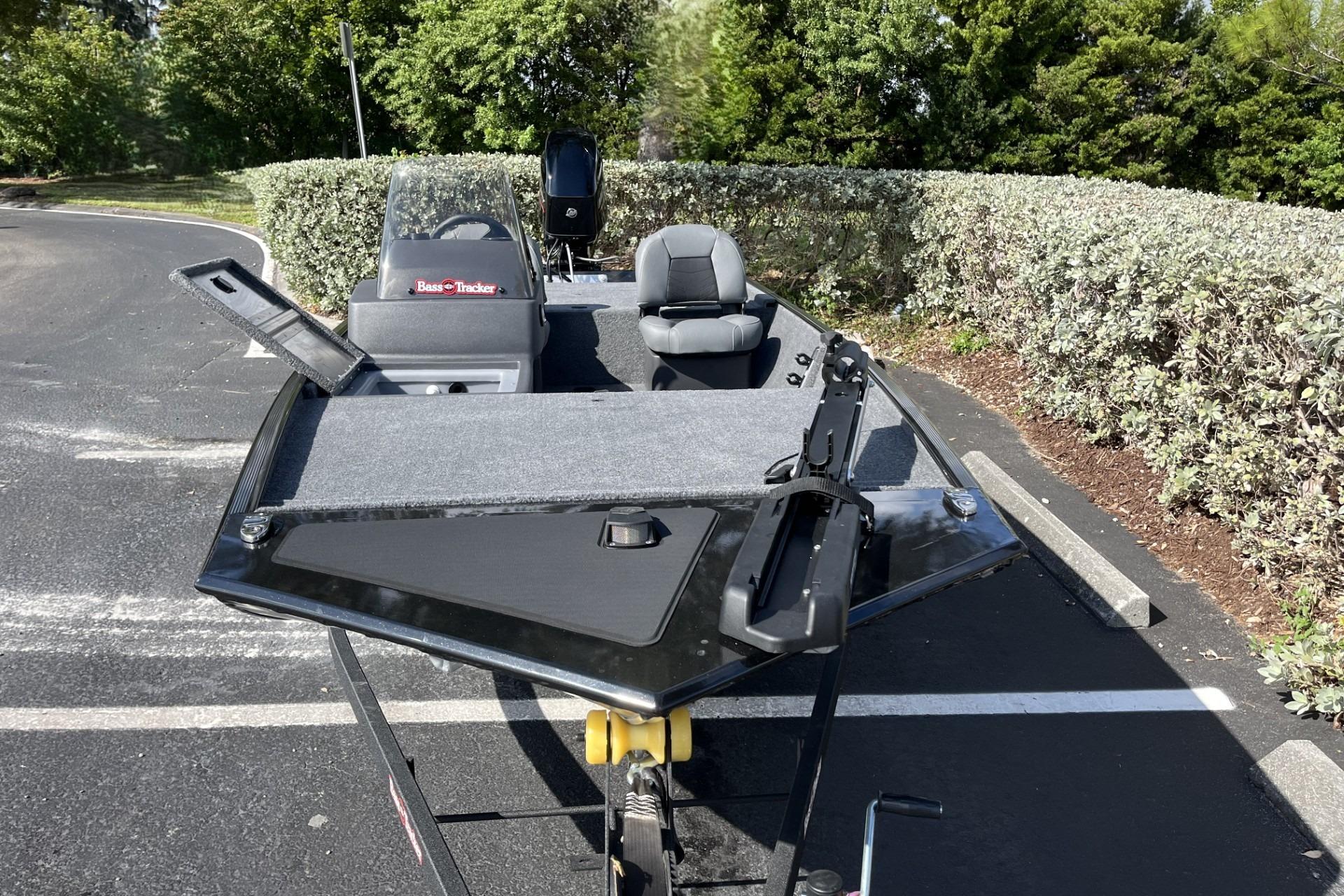 2026 Tracker Bass Tracker Classic XL boat parked on asphalt, surrounded by greenery.
