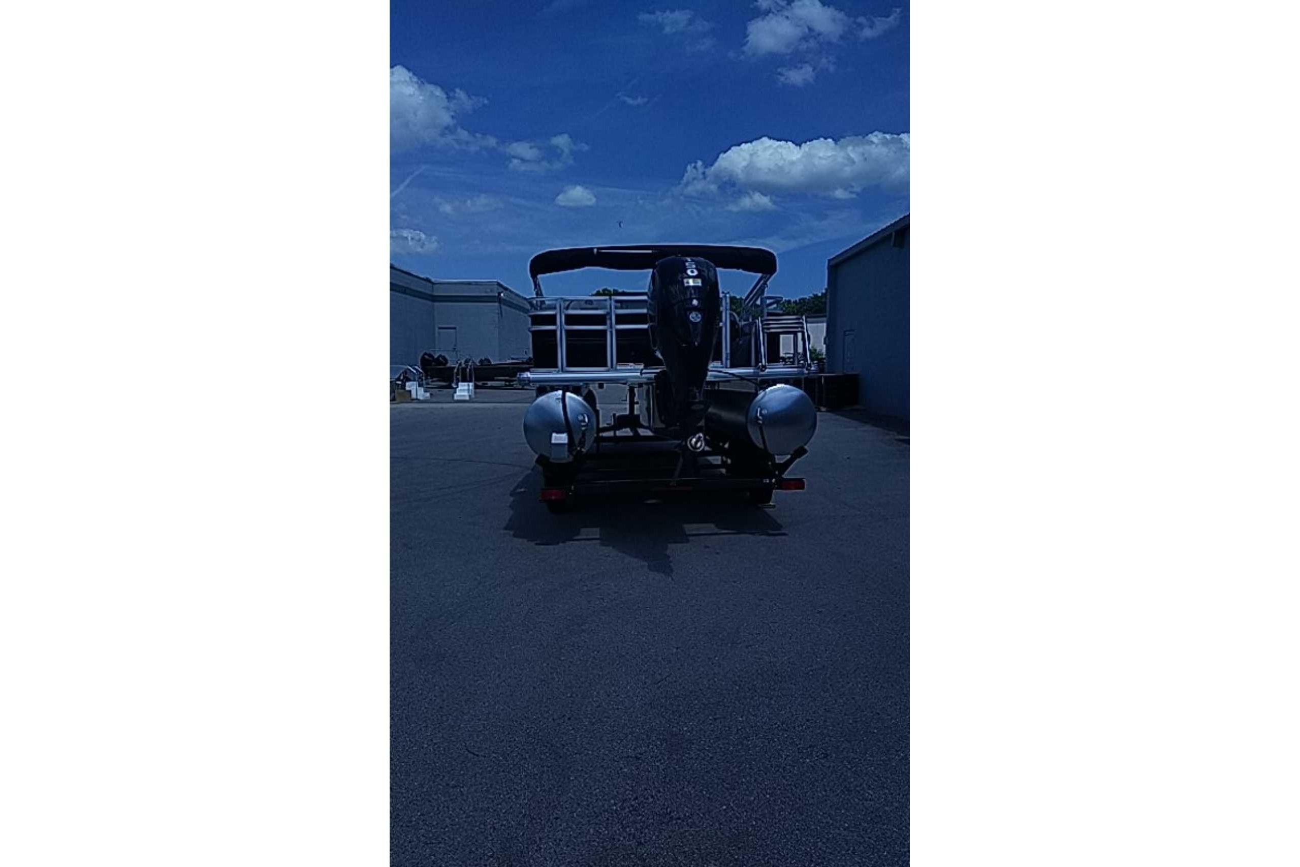 2026 Sun Tracker SportFish 22 DLX pontoon boat with dual engines, parked outdoors.