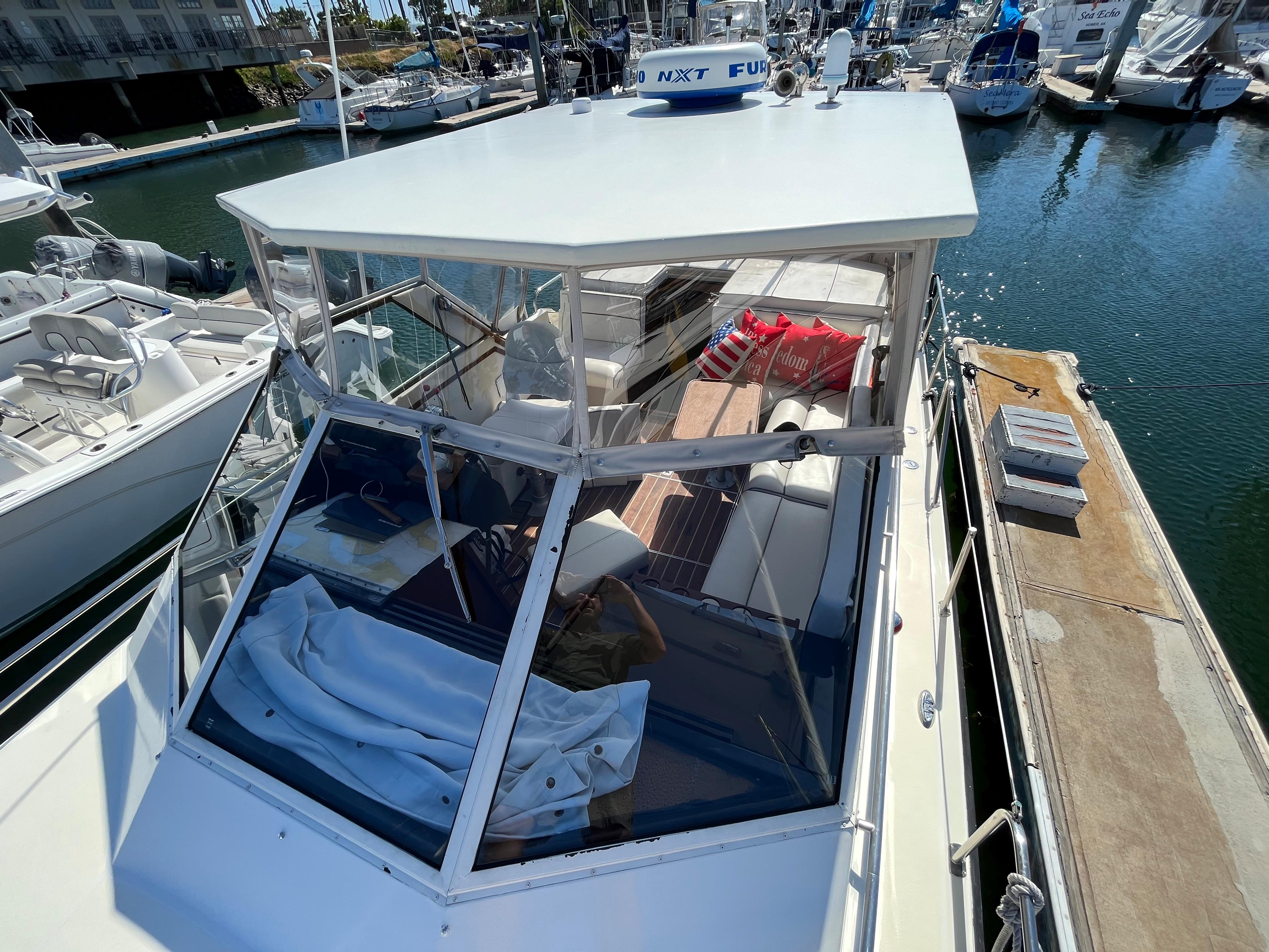 1987 Scand Baltic boat docked at a marina, featuring a covered cockpit and seating area.