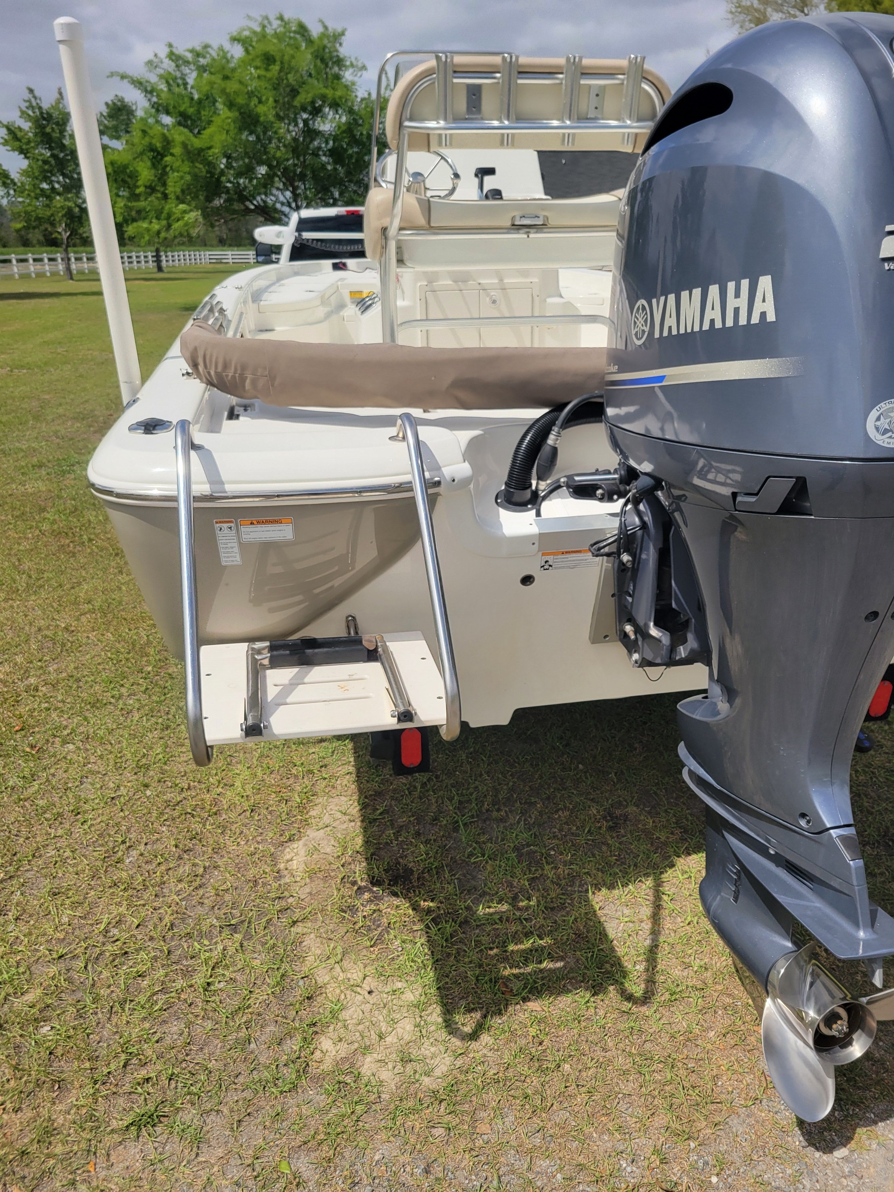 A boat with a Yamaha motor is on a trailer on grass.