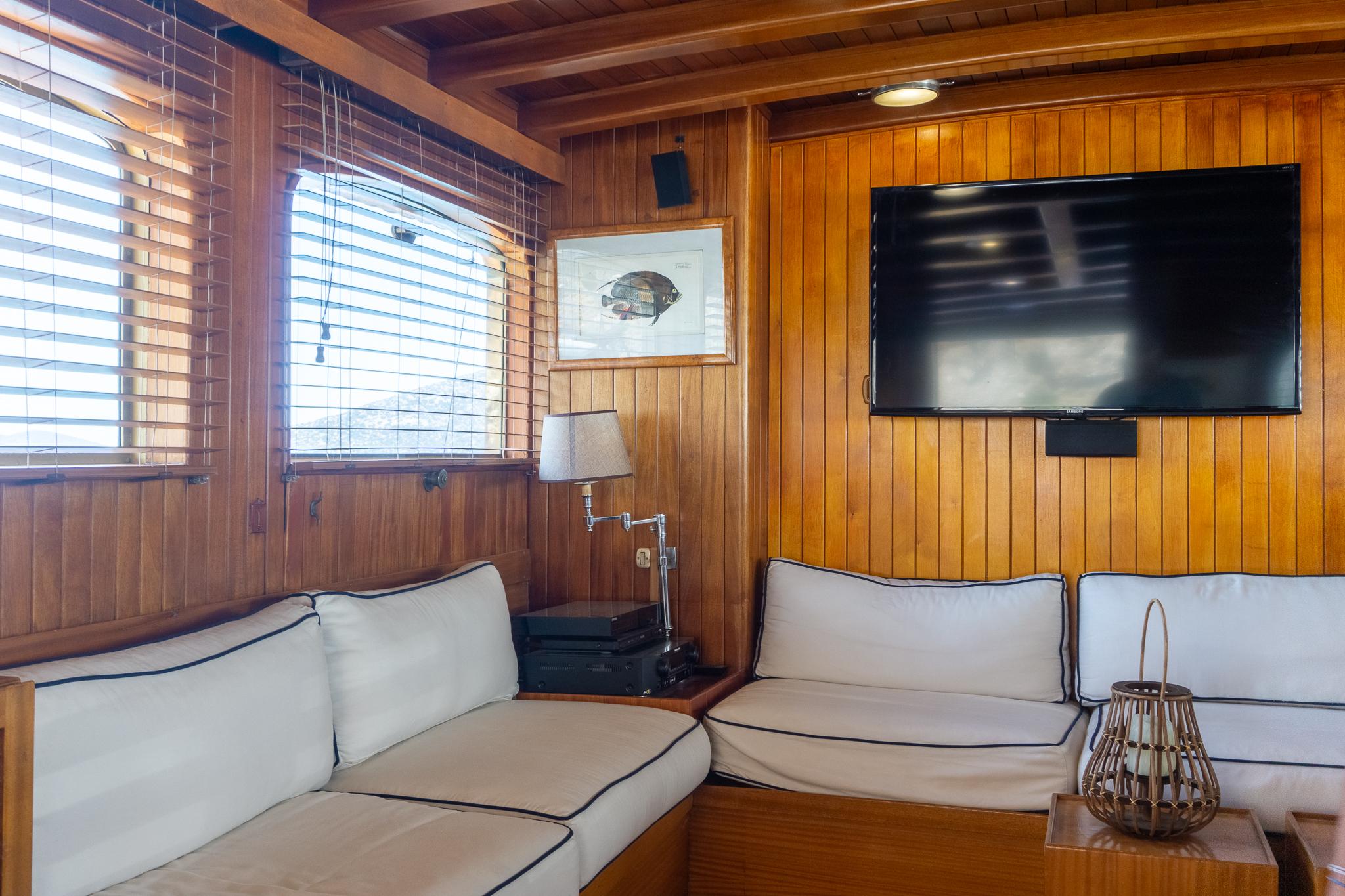 Luxurious wooden interior of a 1969 Psarros Shipyard yacht with cozy seating and modern amenities.