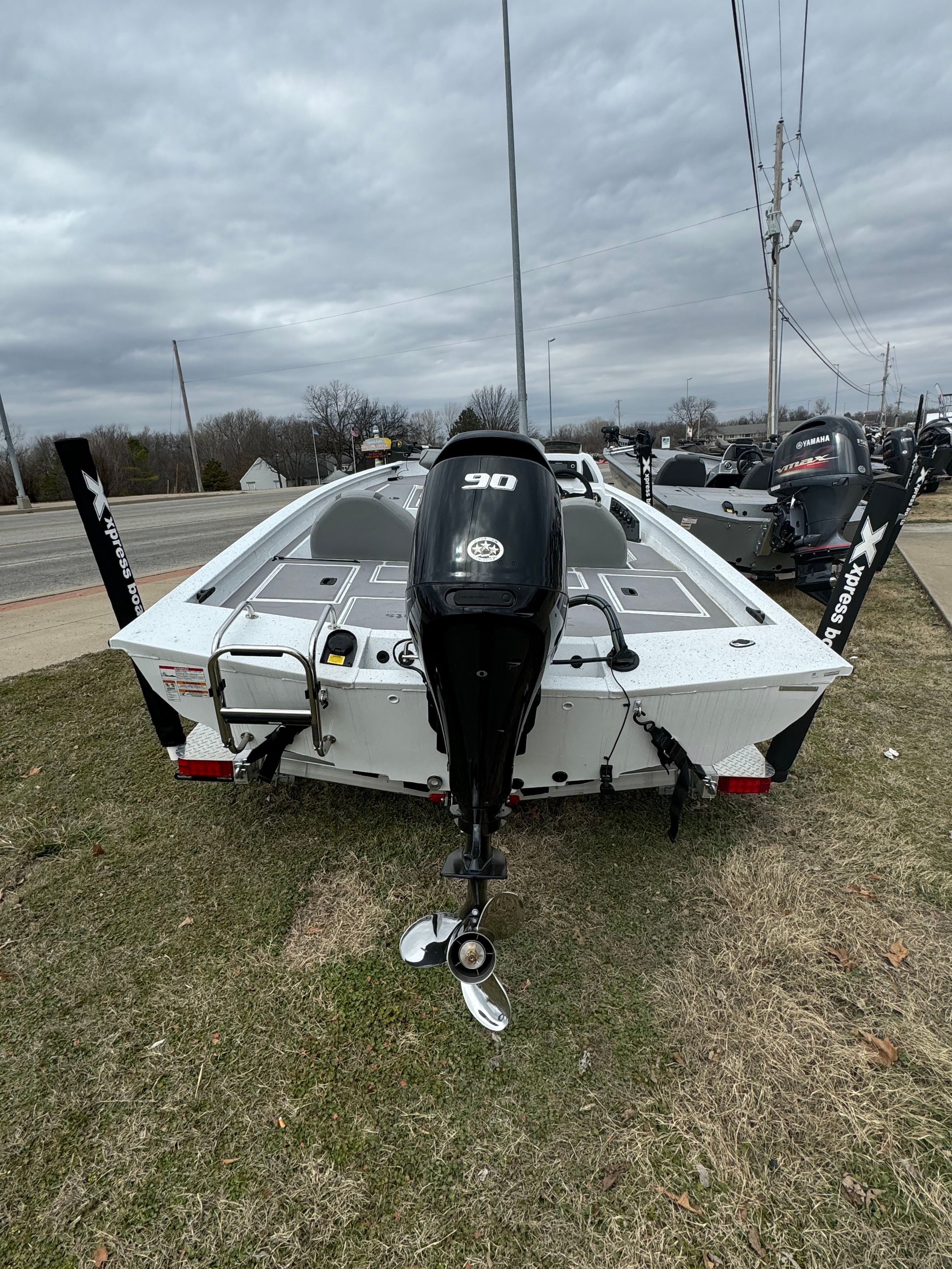 2024 Xpress H17C Crappie boat with outboard motor, parked on grass.