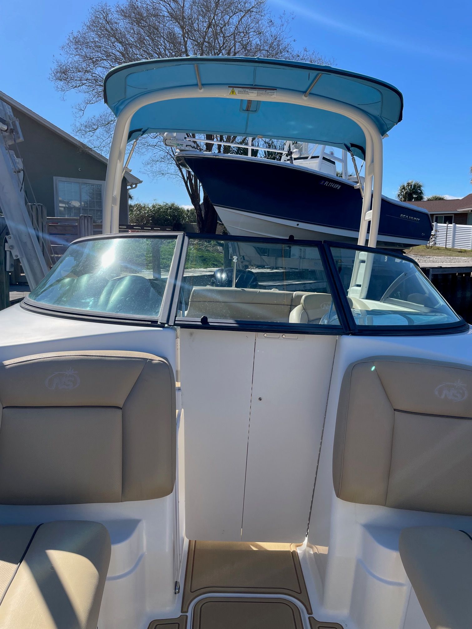 2019 NauticStar 243DC Sport Deck with blue bimini top and beige interior.