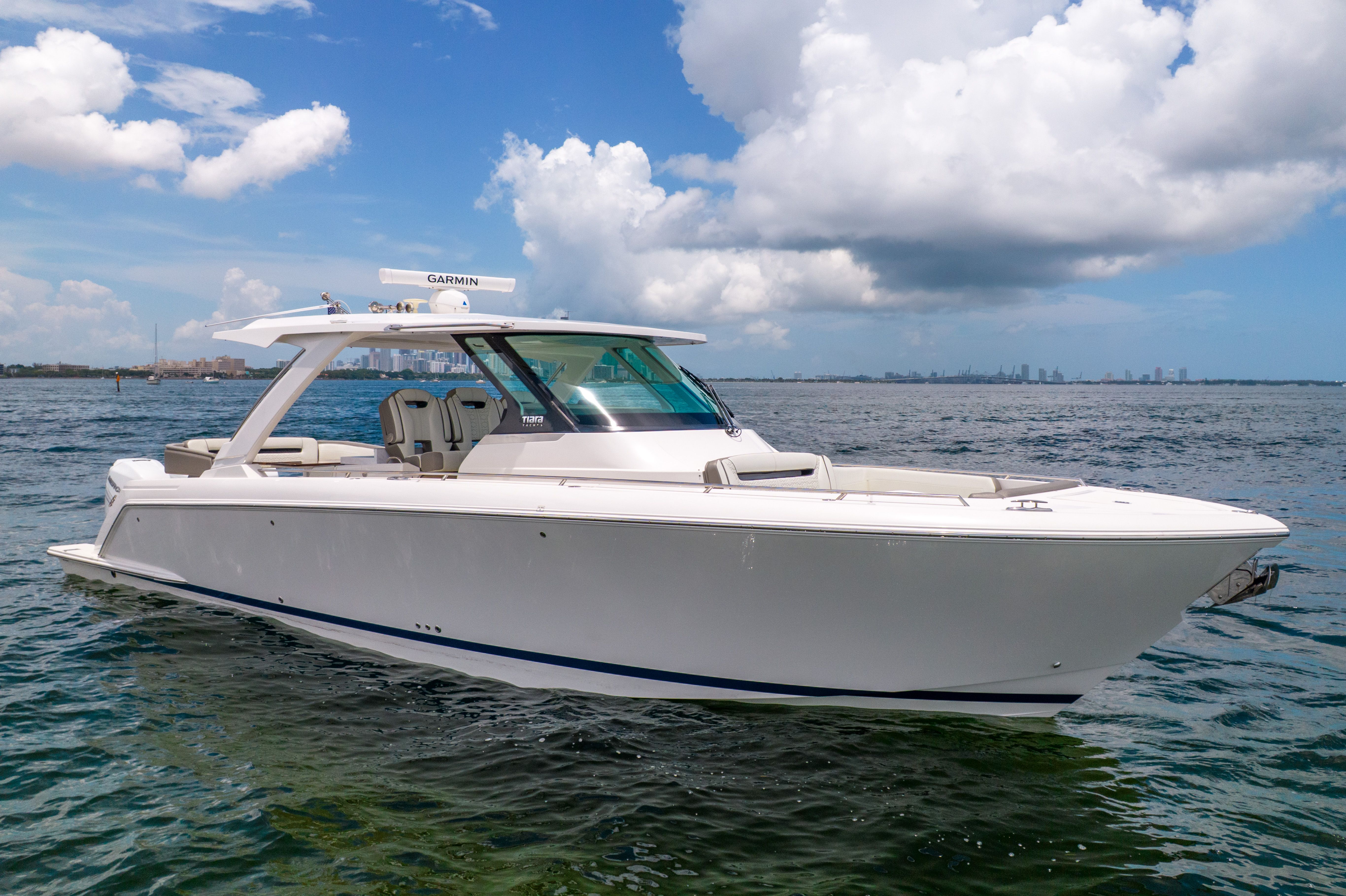 The 2023 Tiara Yachts 38 LS is a sleek motorboat on calm water under a cloudy sky.