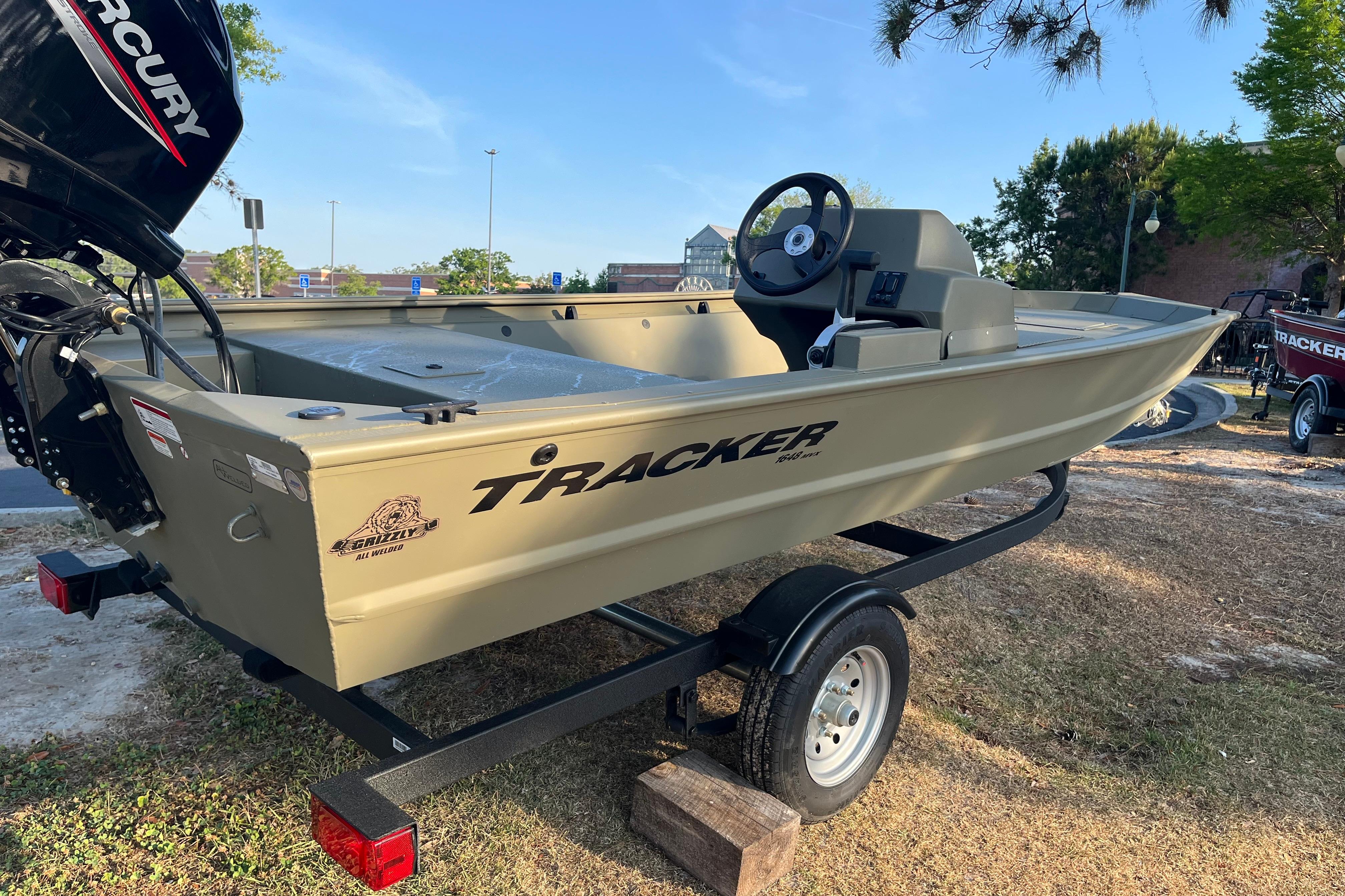 2026 Tracker Grizzly 1648 SC boat on trailer, featuring Mercury engine, parked outdoors.