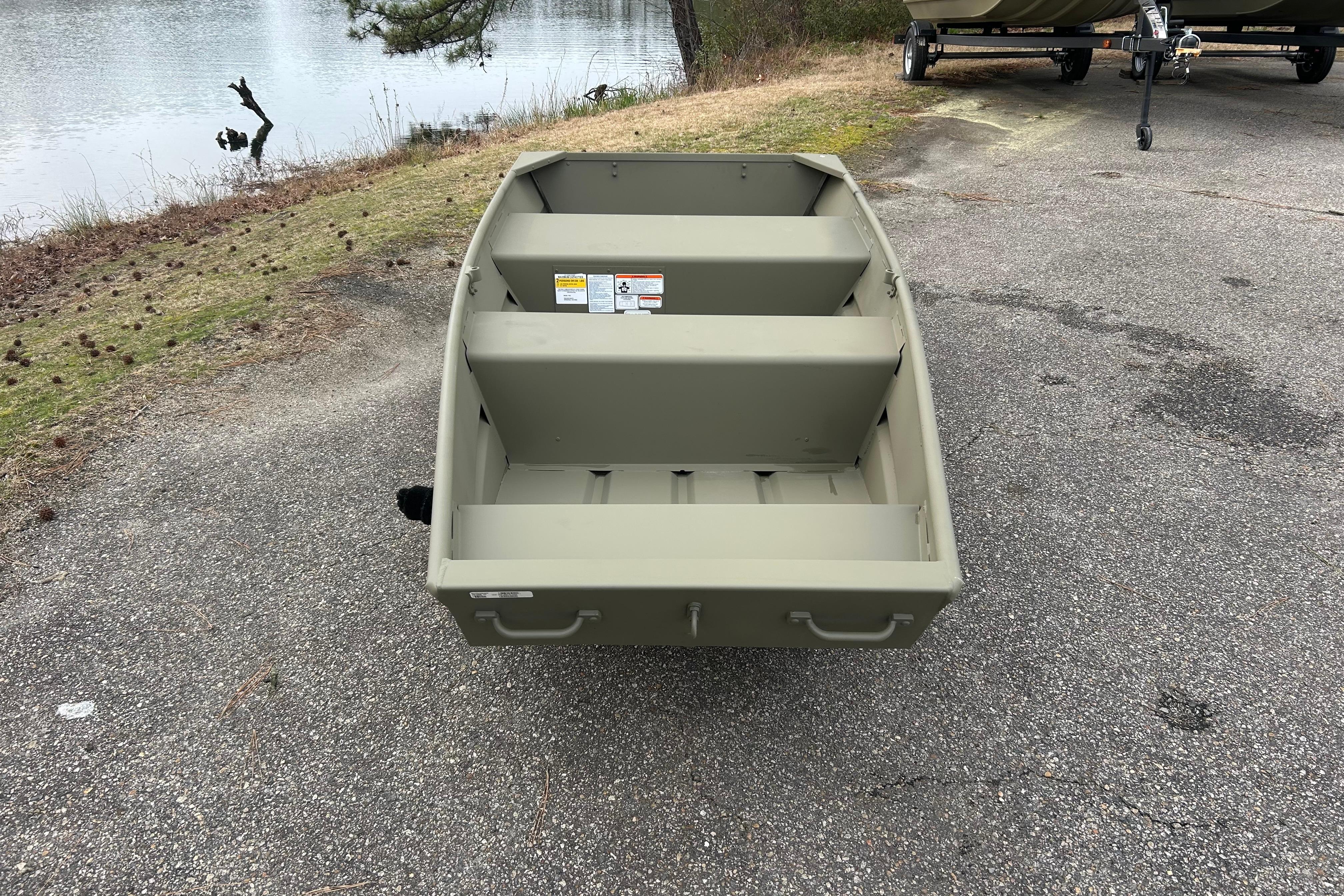 2026 Tracker Grizzly 10 Jon boat on lakeside pavement, ready for water adventures.