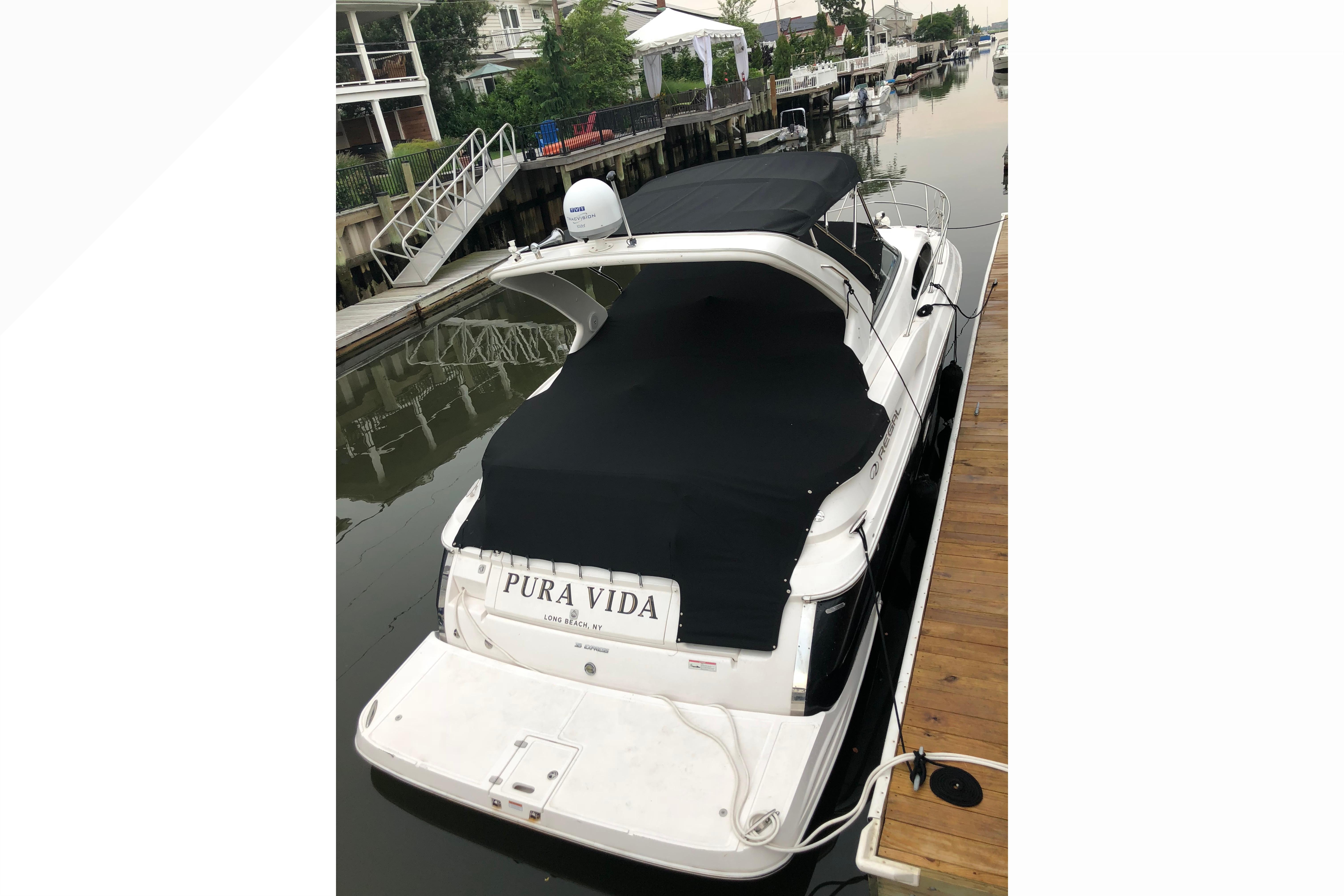 2012 Regal 35 Express Cruiser docked, covered, with "Pura Vida" on the stern.