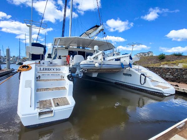 2009 Catana 65 yacht docked with tender boat, clear sky background.