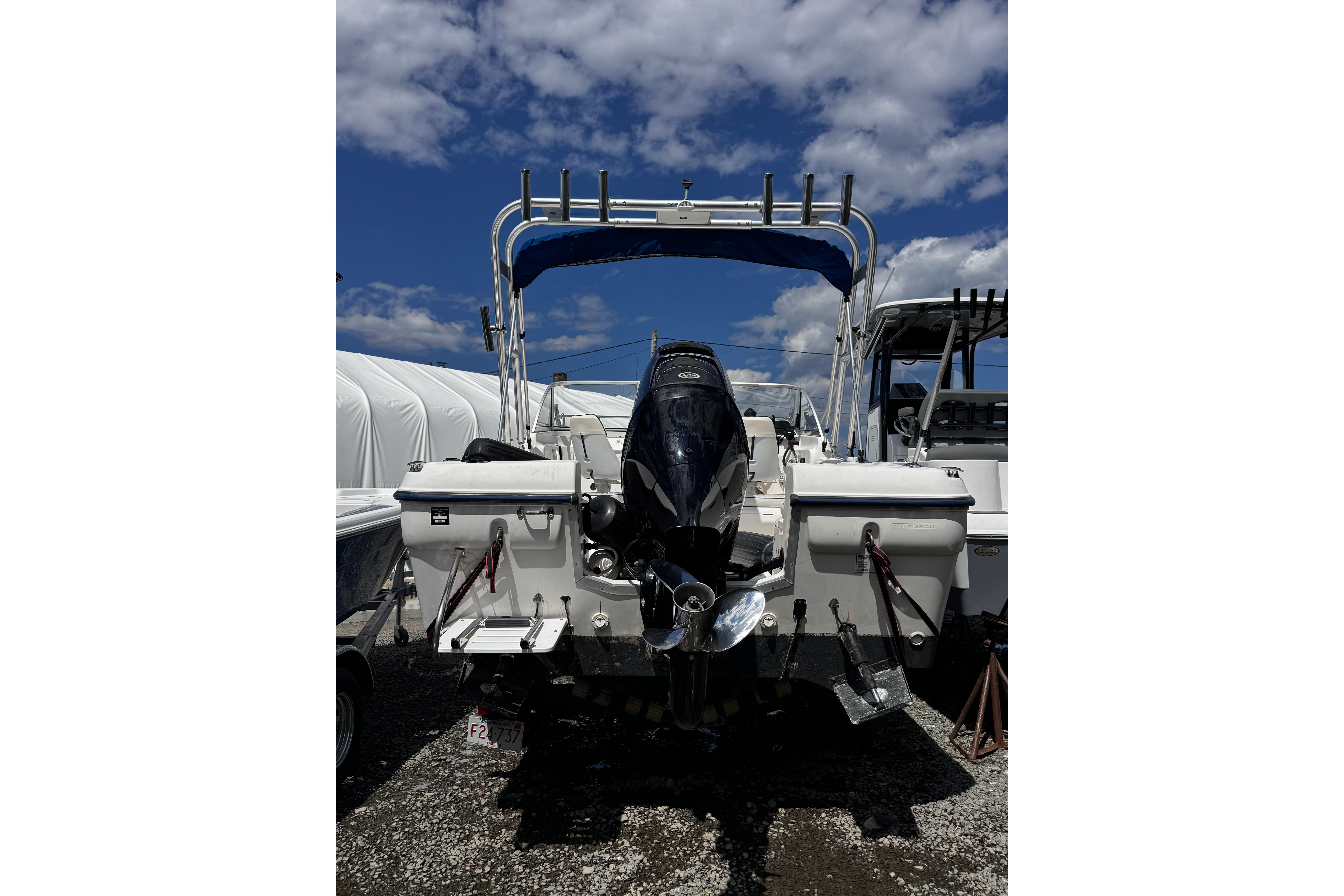 2003 Palm Beach 2200 Dual Console boat with outboard motor, parked under a blue sky.