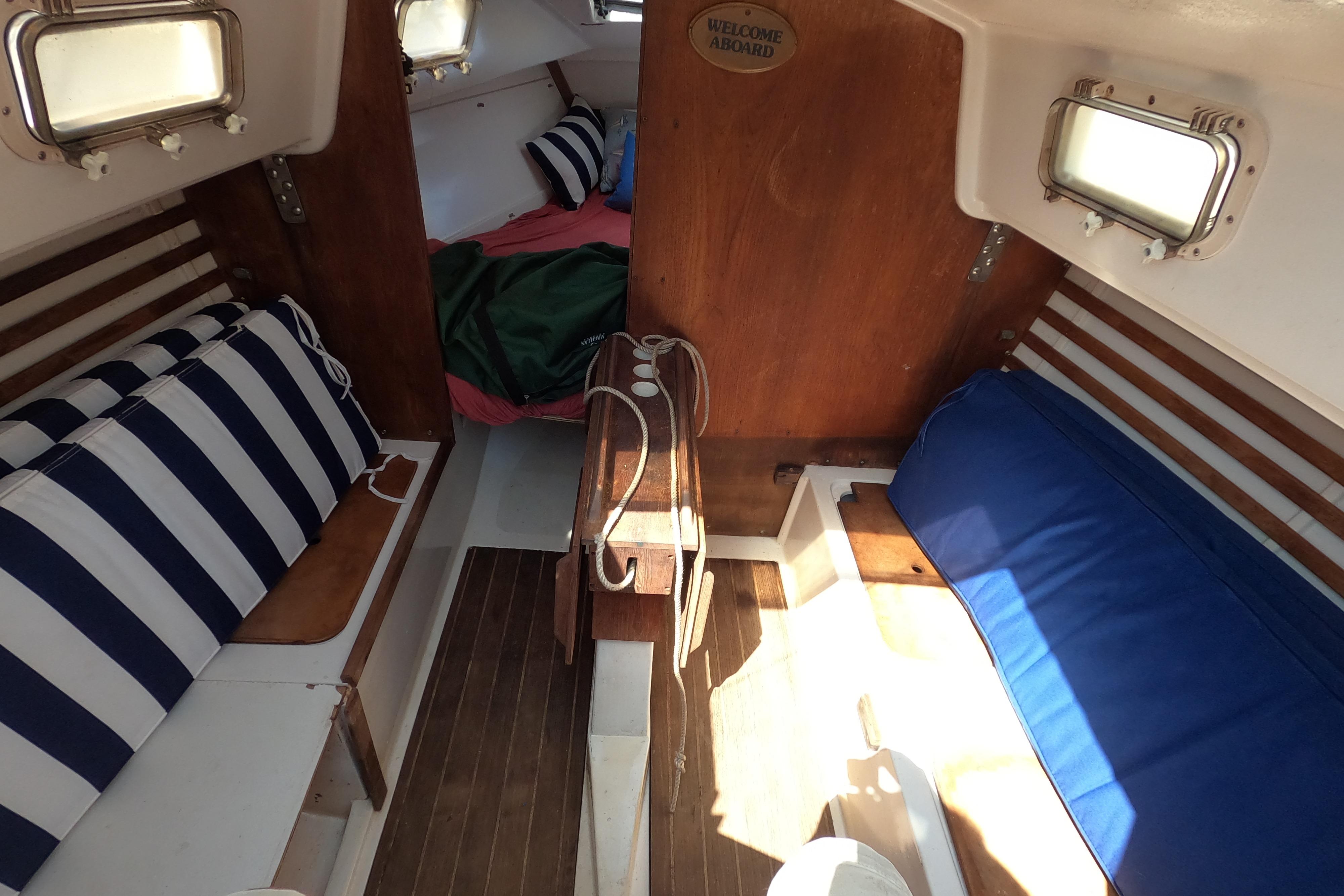 Interior of a 1984 Hunter 22 sailboat with striped cushions and wooden accents.