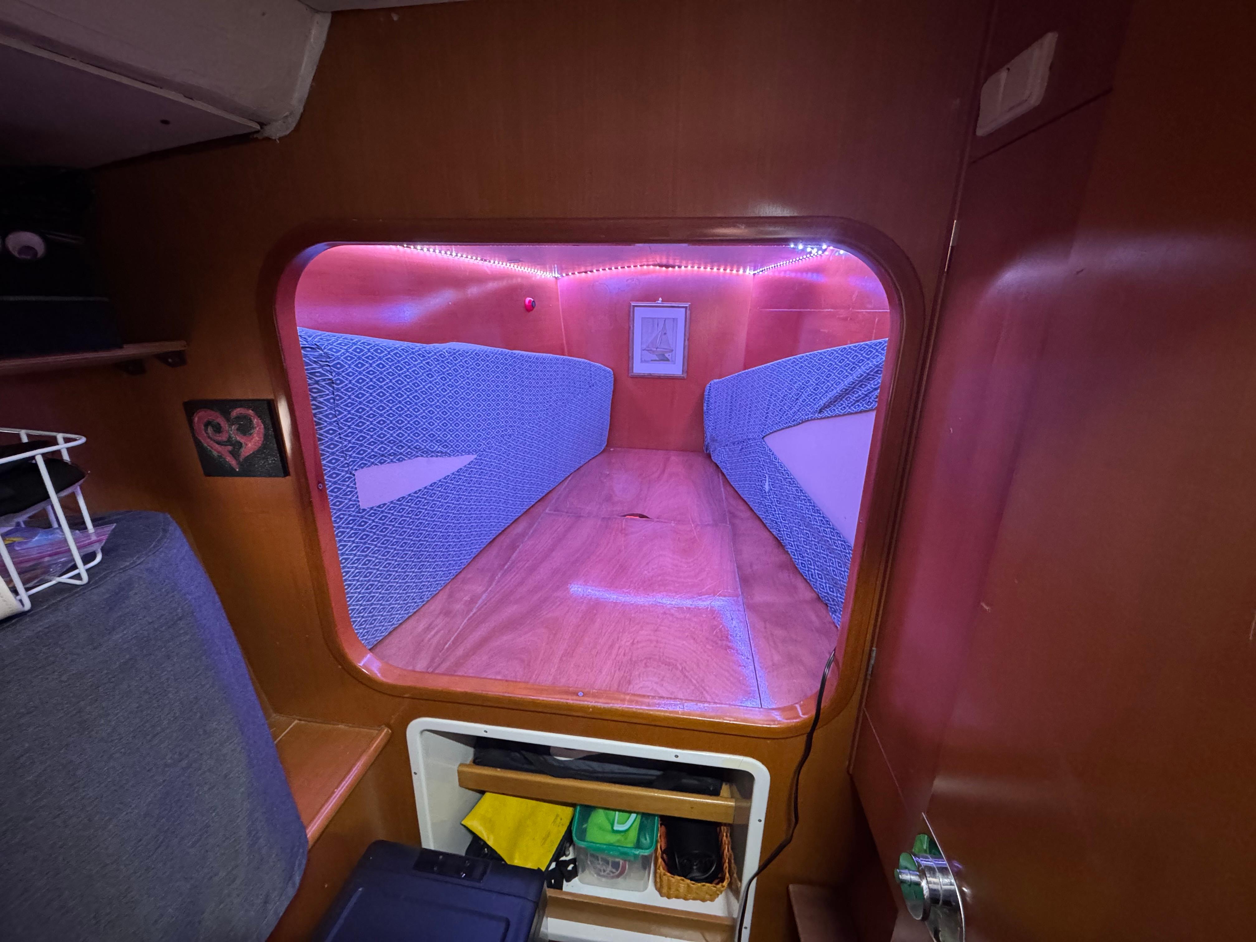Cozy cabin interior of 2004 Lagoon 380 catamaran with ambient lighting and storage.