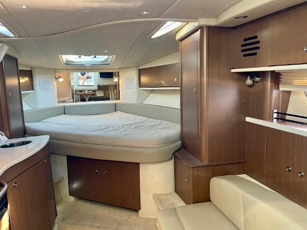 2014 Sea Ray 330 Sundancer cabin interior with bed, wood cabinetry, and seating area.