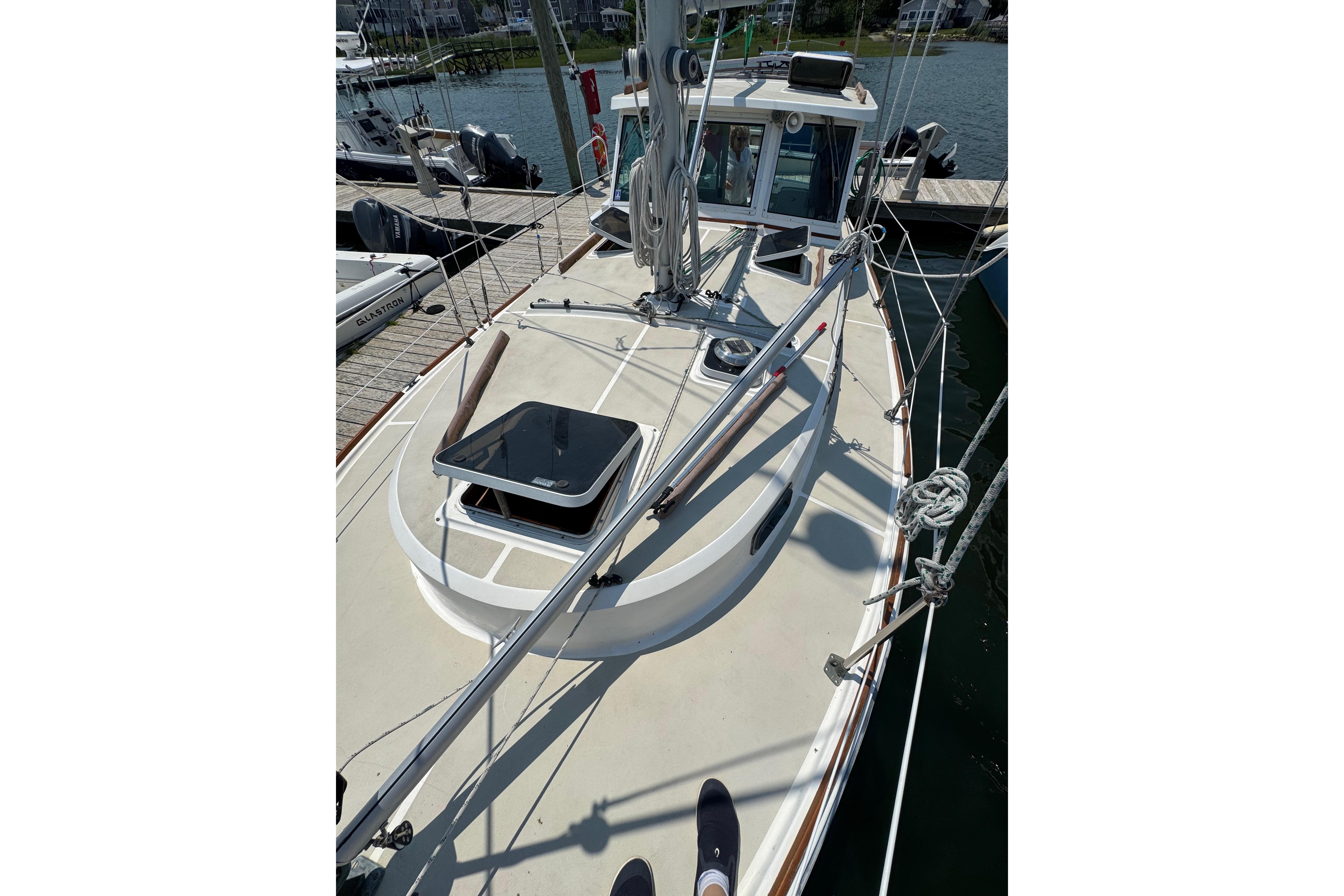 1989 Cape Dory 30 Motorsailer deck view at marina, showcasing rigging and hatch.