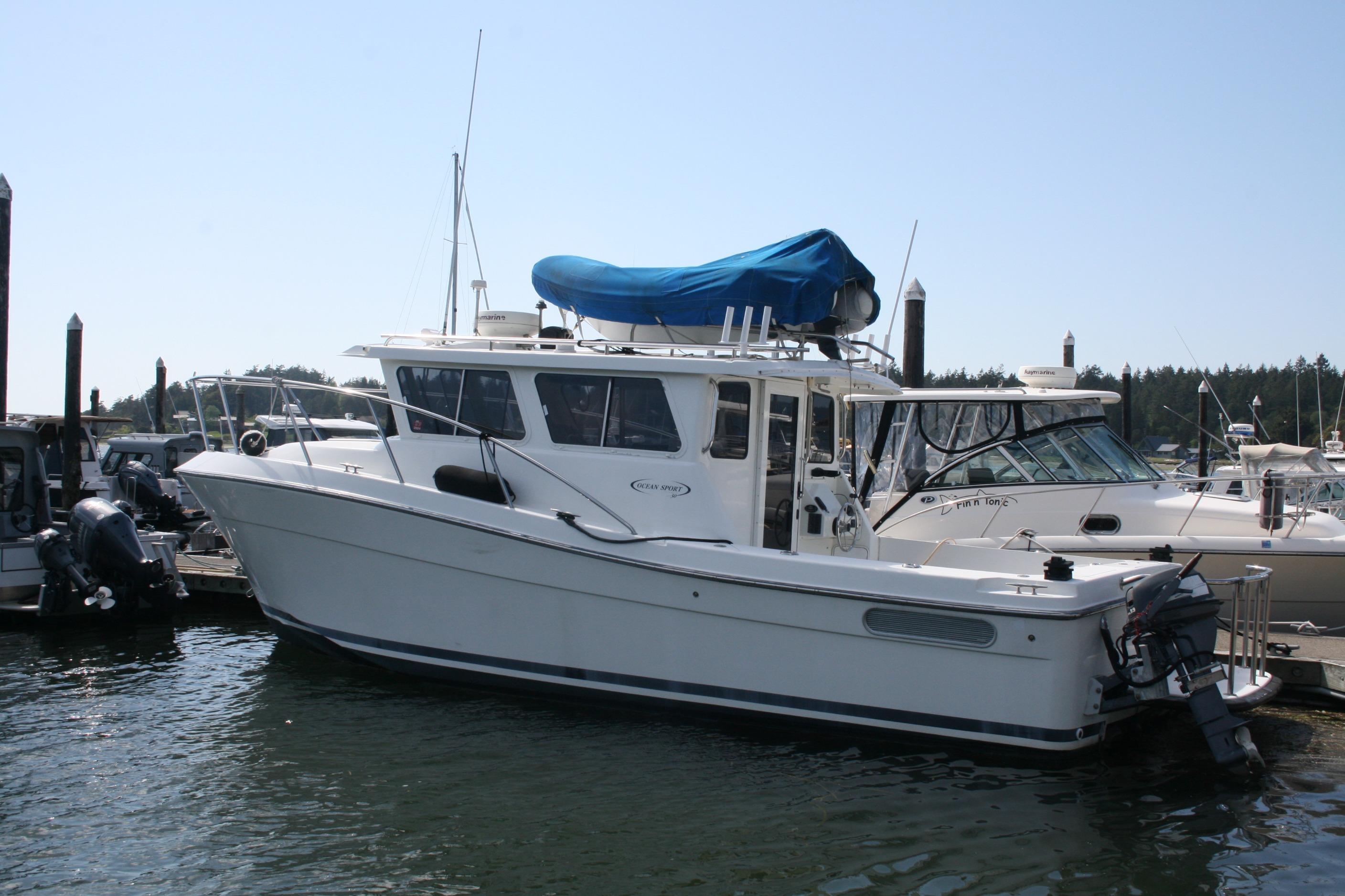 2005 Ocean Sport 30' boat docked at marina, featuring sleek design and covered upper deck.