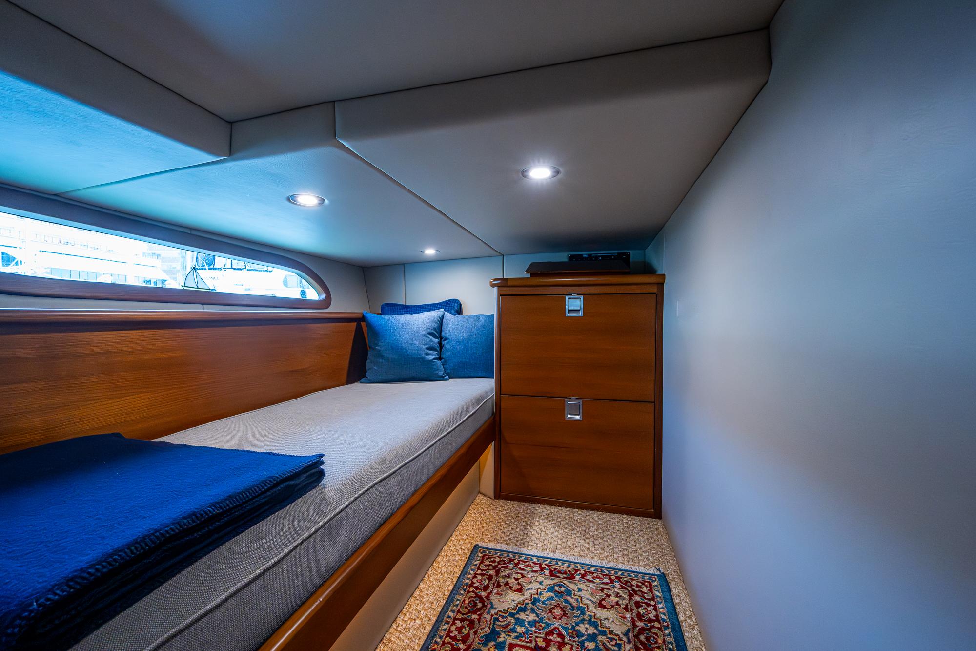 Cabin interior of 2017 Grand Banks 44 Eastbay SX with cozy bed and wooden storage.