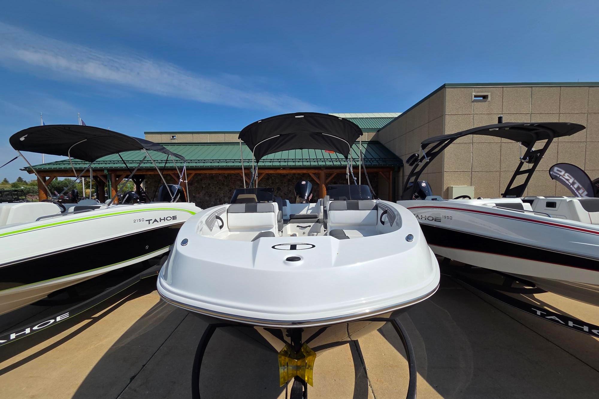 2025 Tahoe T21 boat displayed outdoors with two other models, featuring sleek design and canopy.