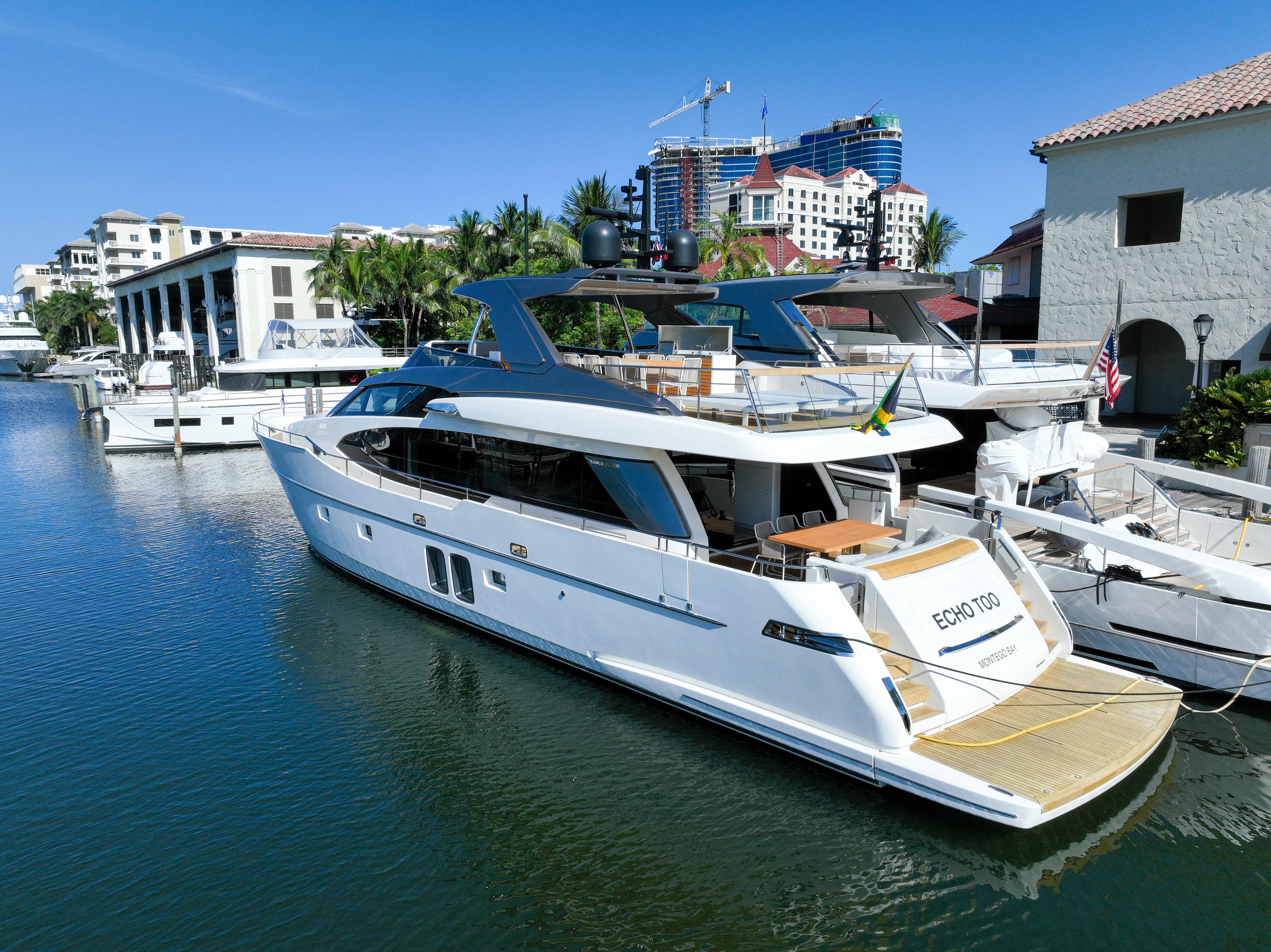 Sanlorenzo SL78 2022 yacht docked in a marina, surrounded by buildings and clear blue sky.