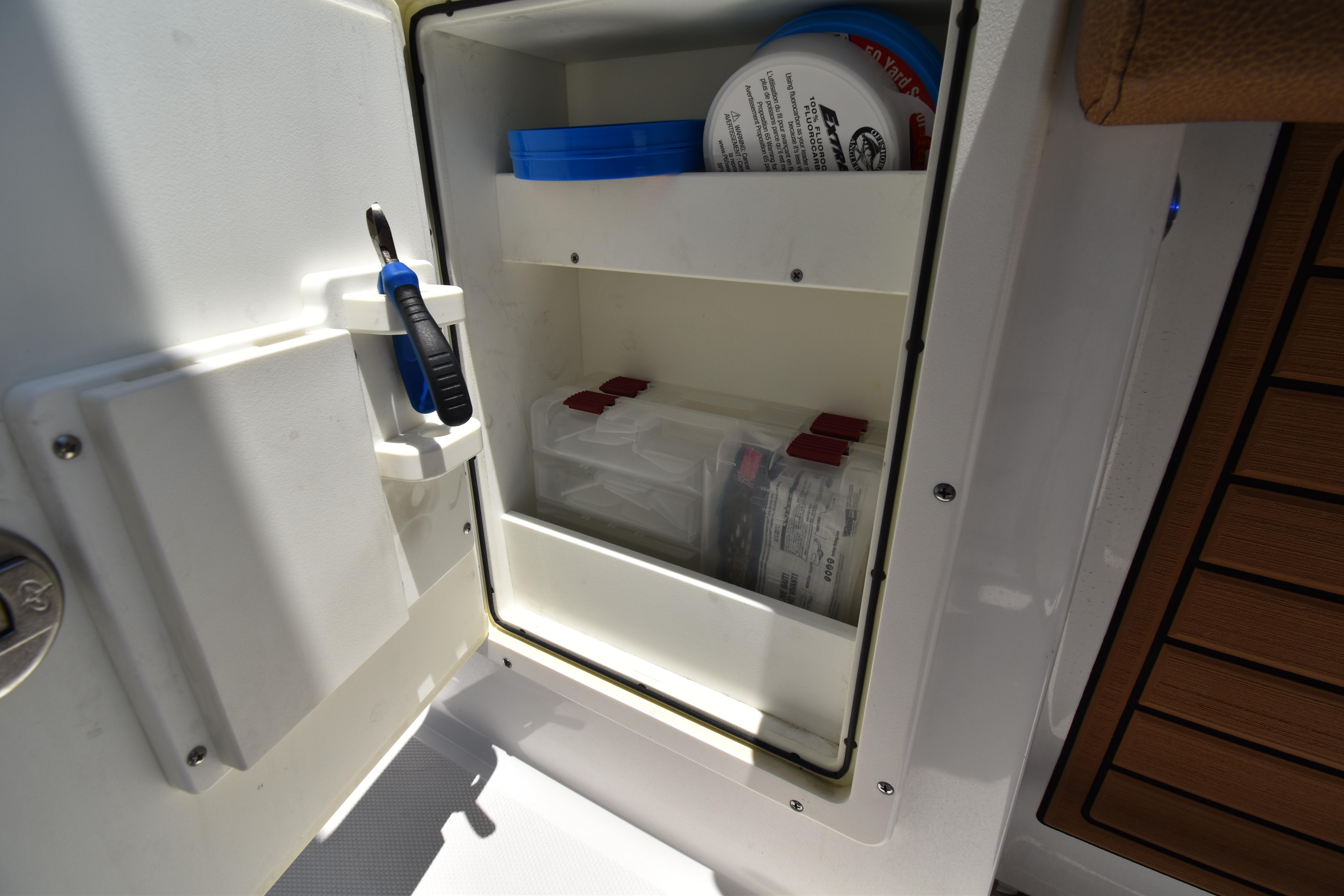 Storage compartment on a 2020 Sea Hunt Ultra 275 SE boat, featuring organized shelves and tools.