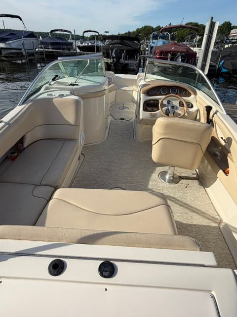 Interior view of a Sea Ray 210 Sundeck boat with beige seating and helm console.