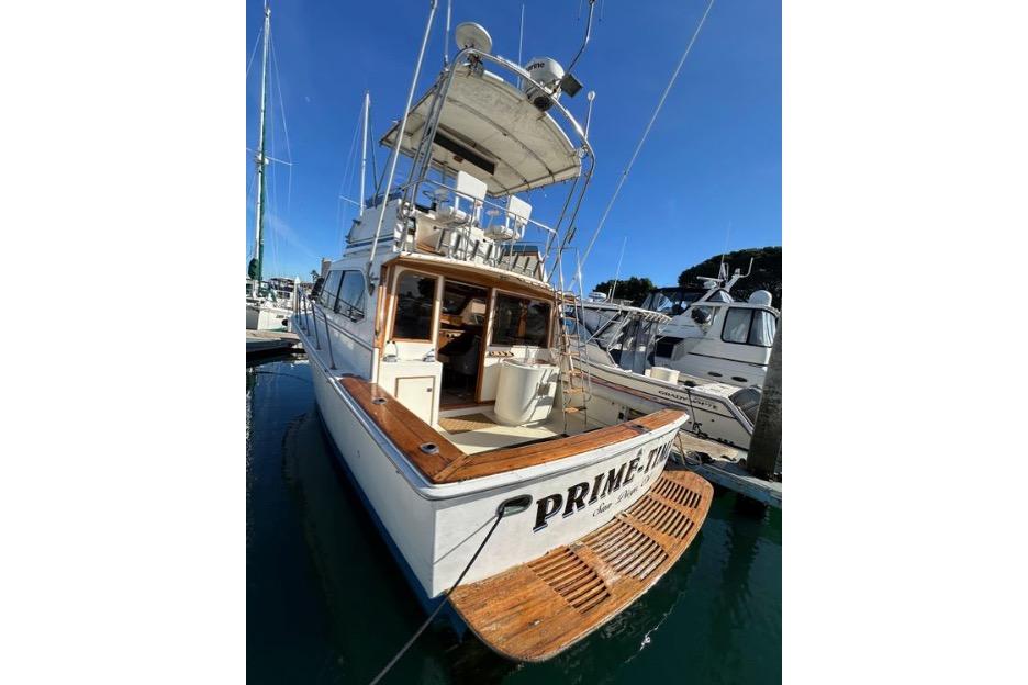 1985 Egg Harbor 33 Sedan boat docked, featuring wooden deck and upper helm.
