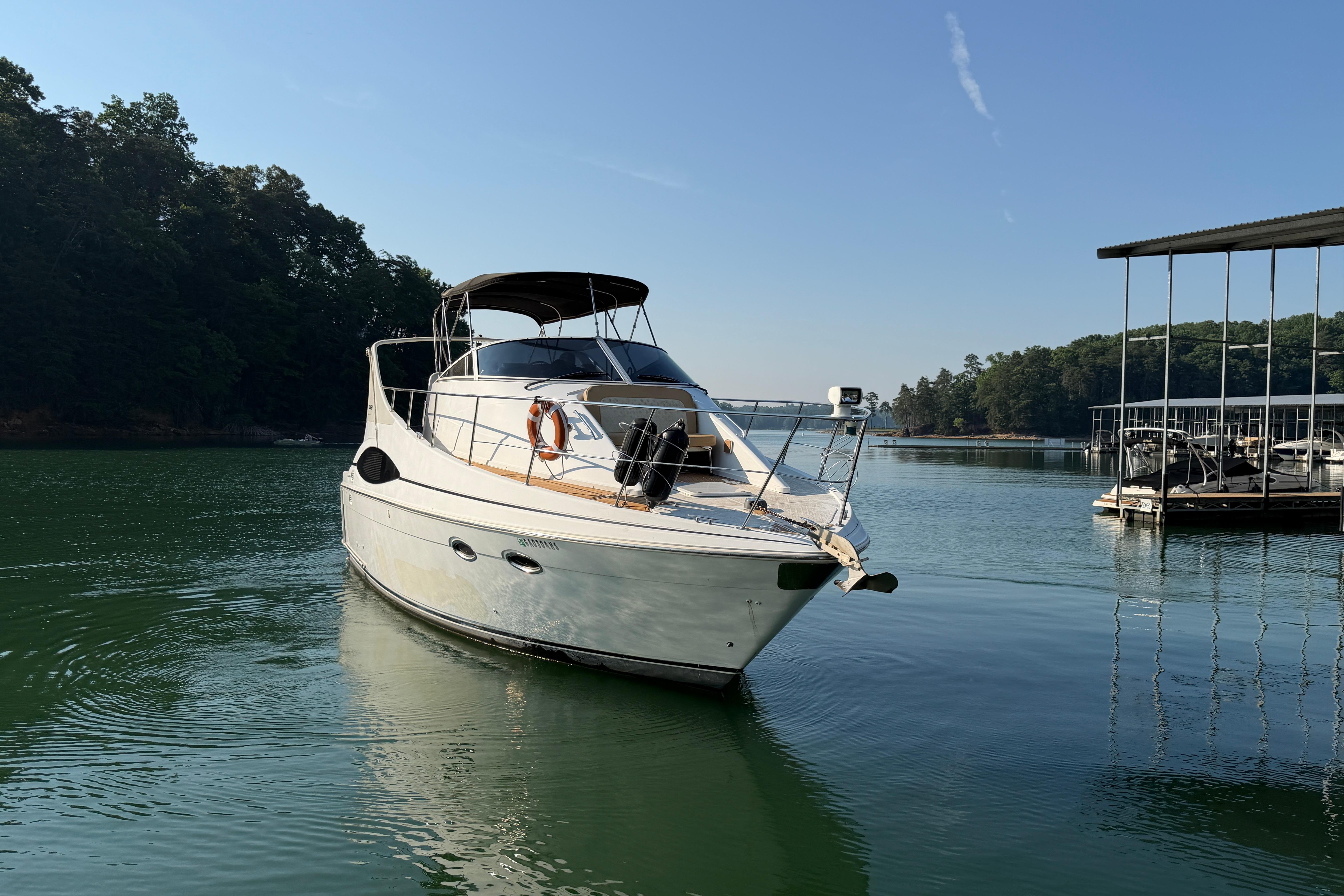 2003 Carver 350 Mariner yacht docked on a serene lake under clear blue skies.