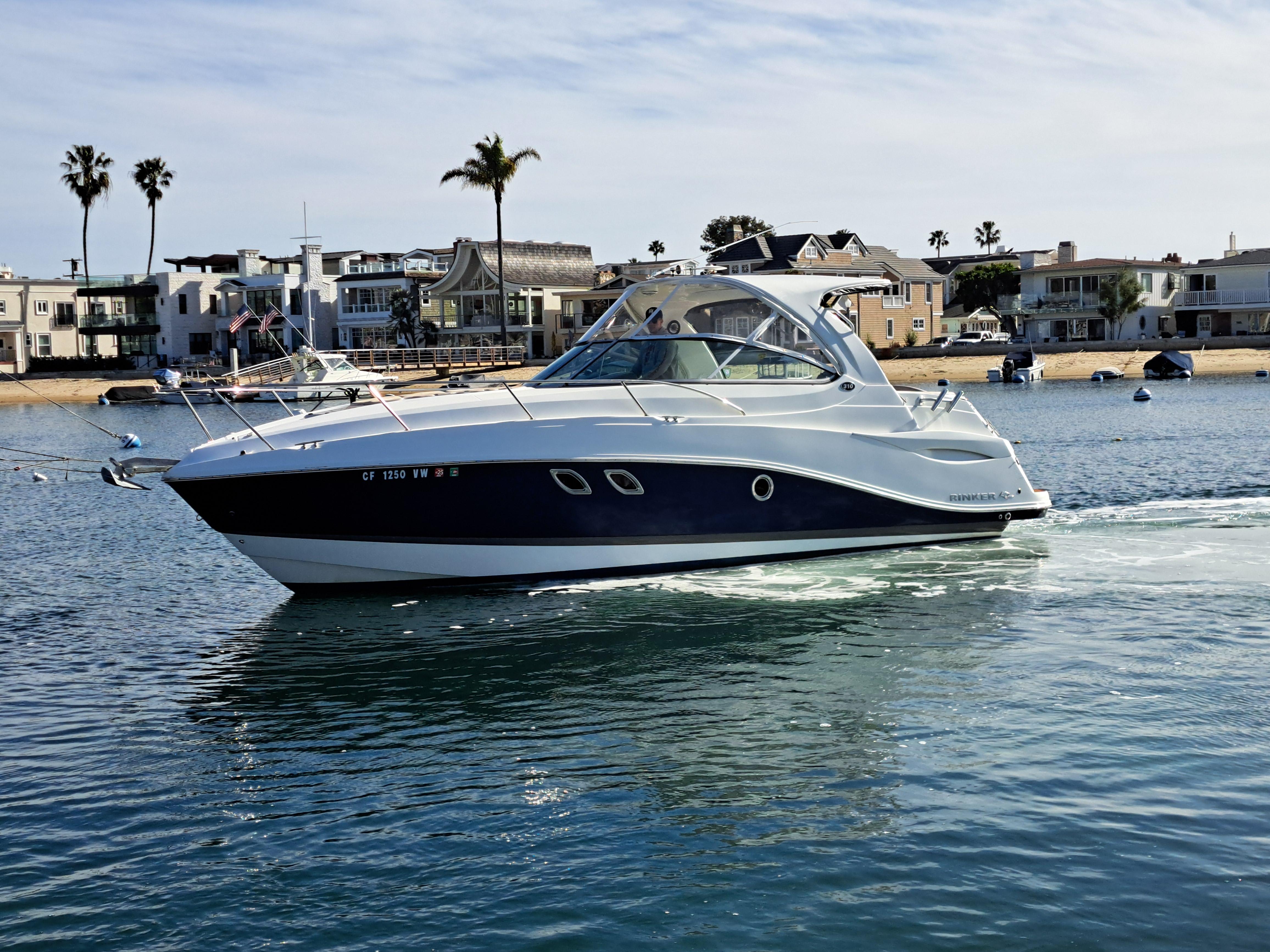2013 Rinker 310 Express Cruiser on calm water near coastal homes.