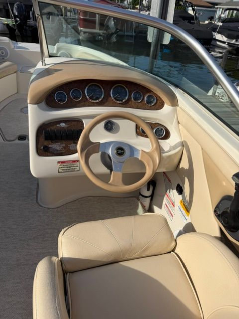 The image shows the cockpit of a Sea Ray 210 Sundeck boat with a beige steering wheel.