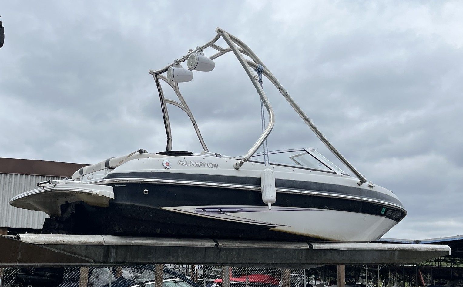 A 2011 Glastron GT 185 boat is on a trailer under a cloudy sky.