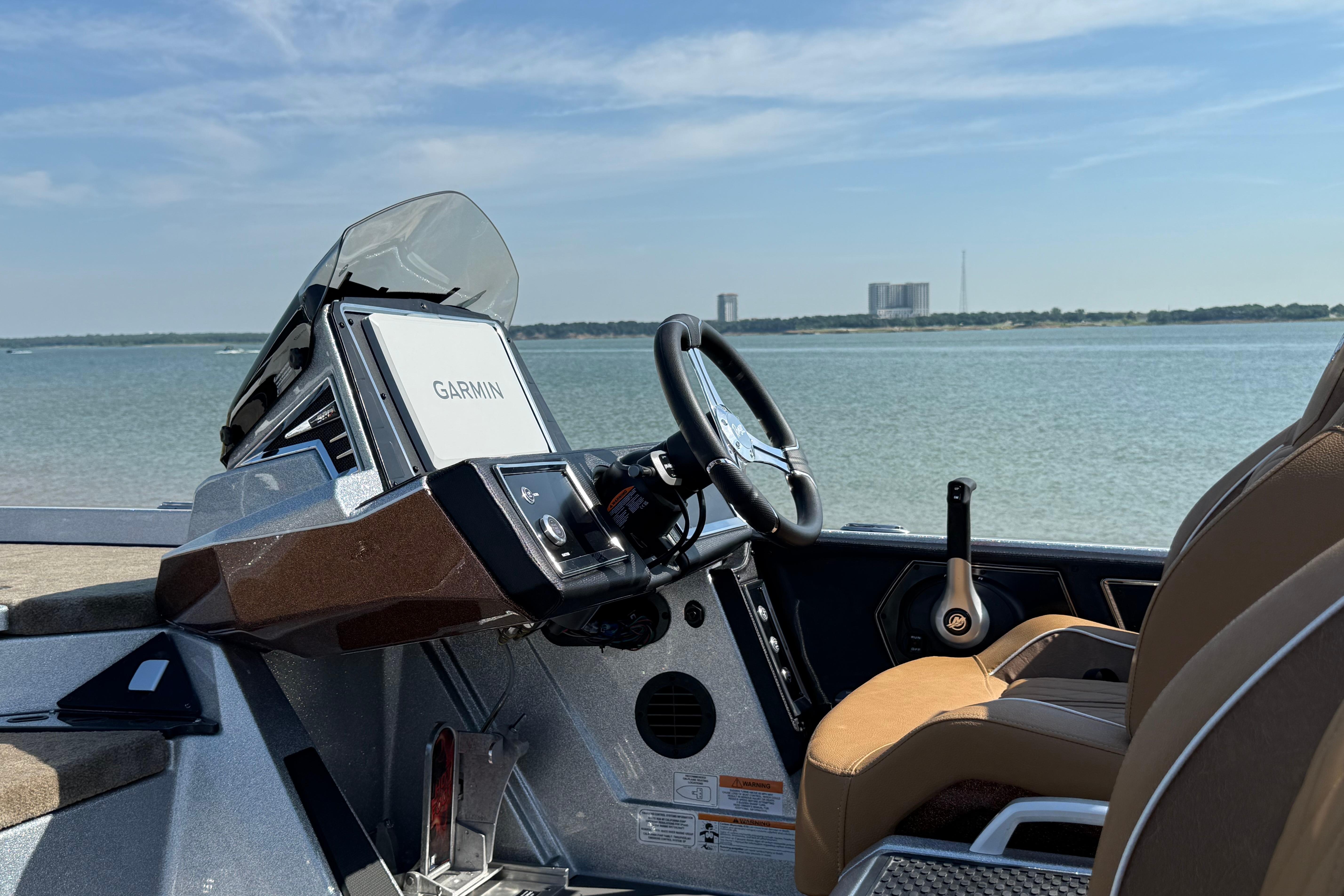 2026 Ranger Z521R boat cockpit with Garmin navigation, overlooking serene water and distant buildings.