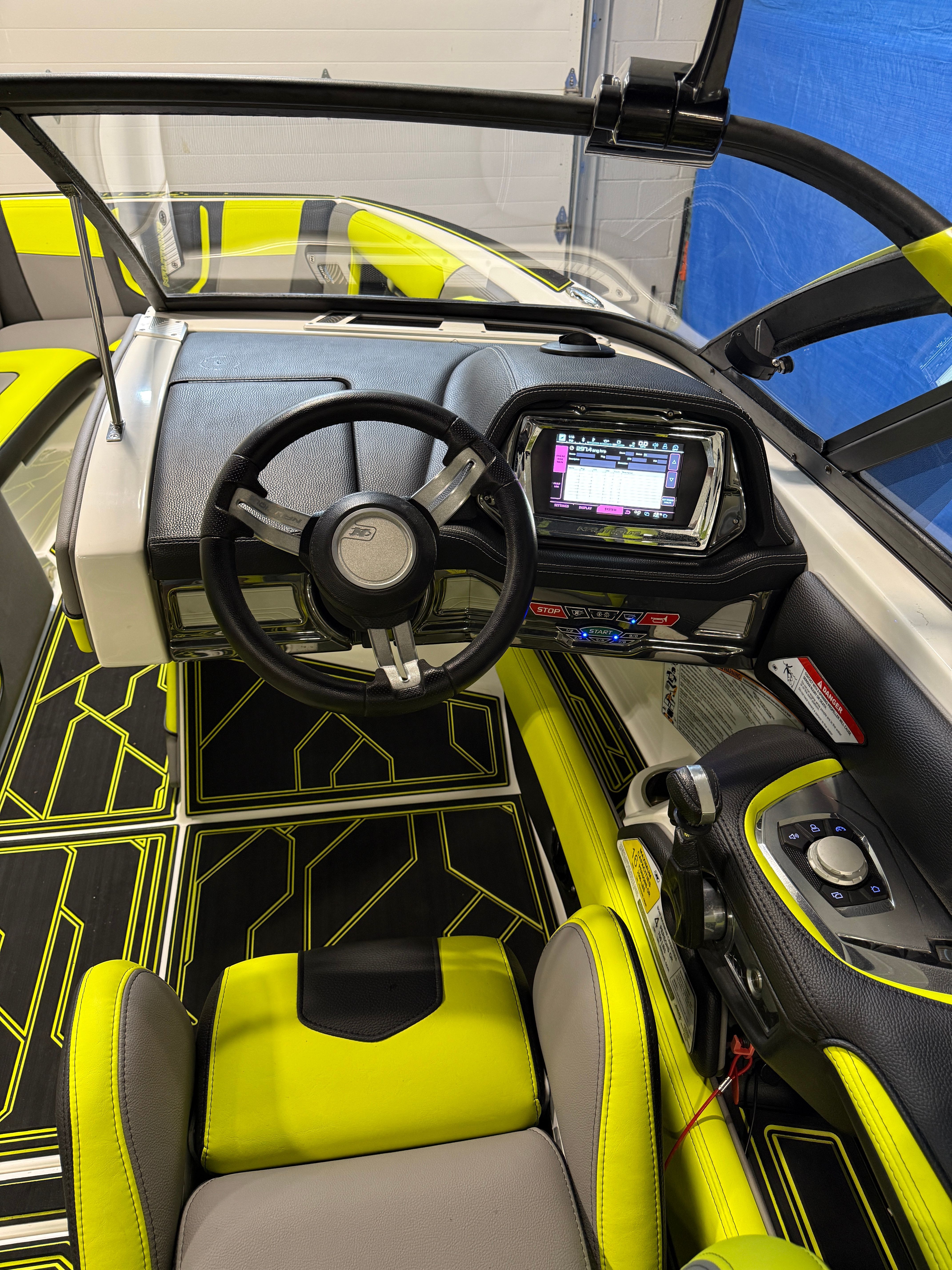 The cockpit of a 2016 Nautique Super Air Nautique G23 with modern steering wheel and touchscreen.