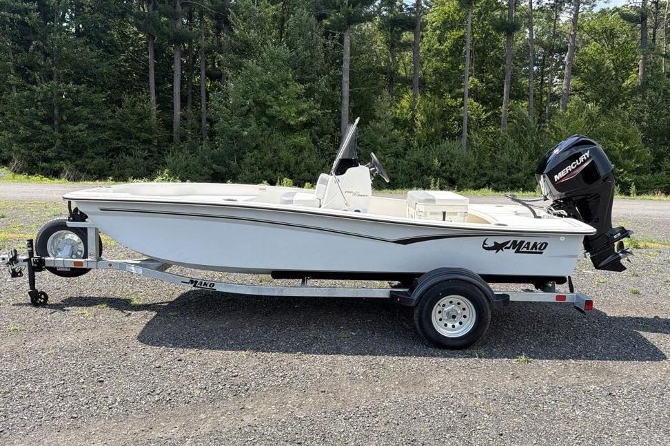 2026 Mako Pro Skiff 15 CC boat on trailer, parked outdoors with forest background.