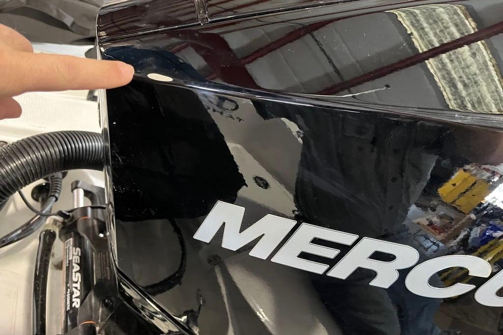 Close-up of a 2026 Tahoe 2150 CC boat engine with a finger pointing.