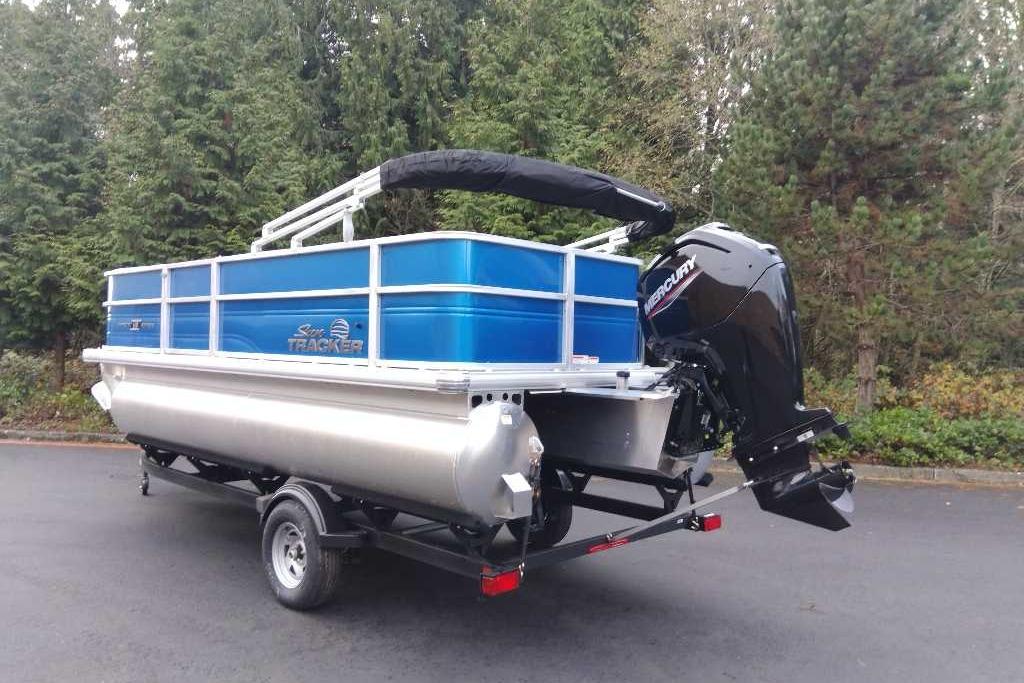 2026 Sun Tracker Party Barge 18 DLX pontoon boat on trailer, surrounded by trees.