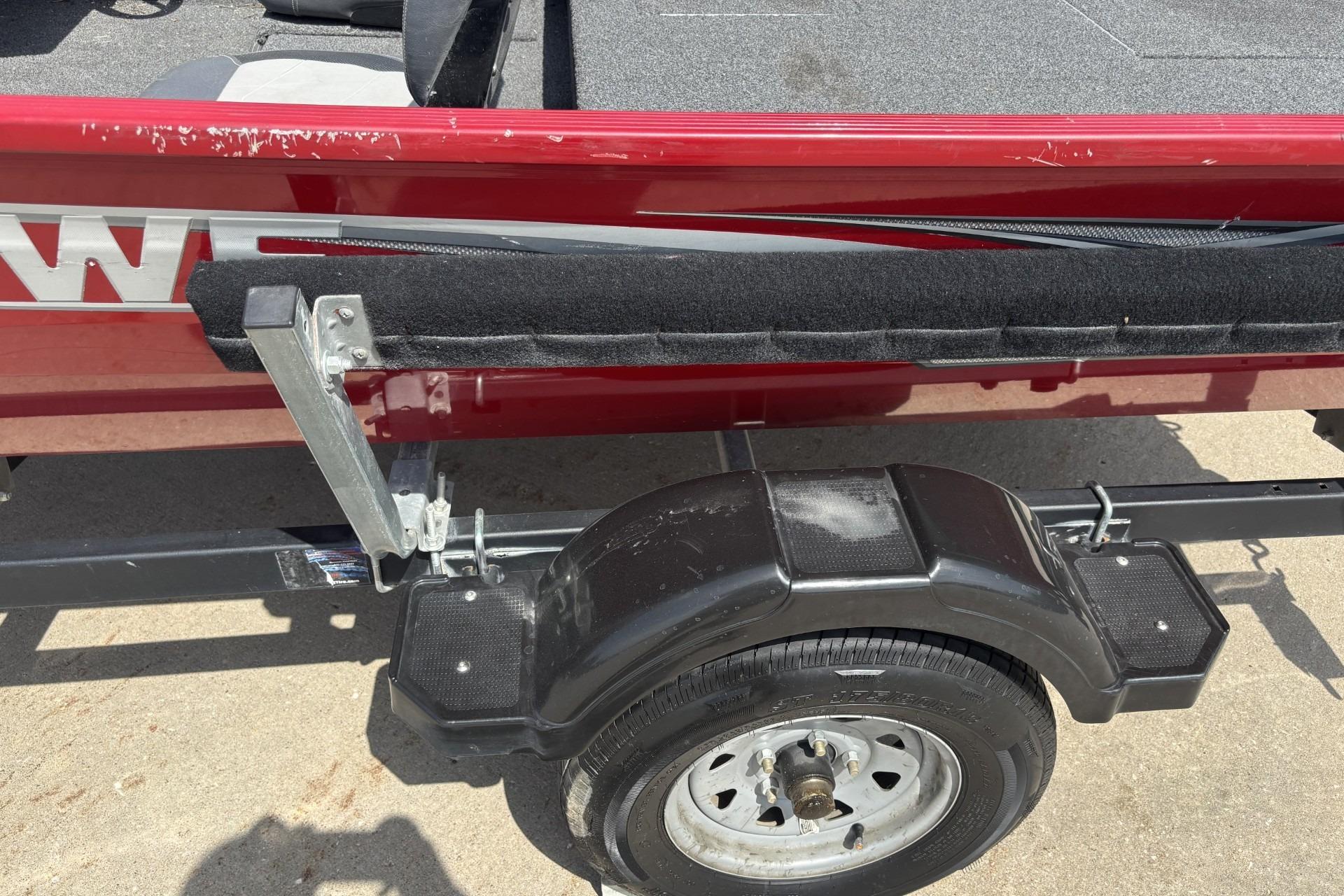 Red 2019 Lowe Skorpion 17 boat trailer with black fender and wheel on concrete.